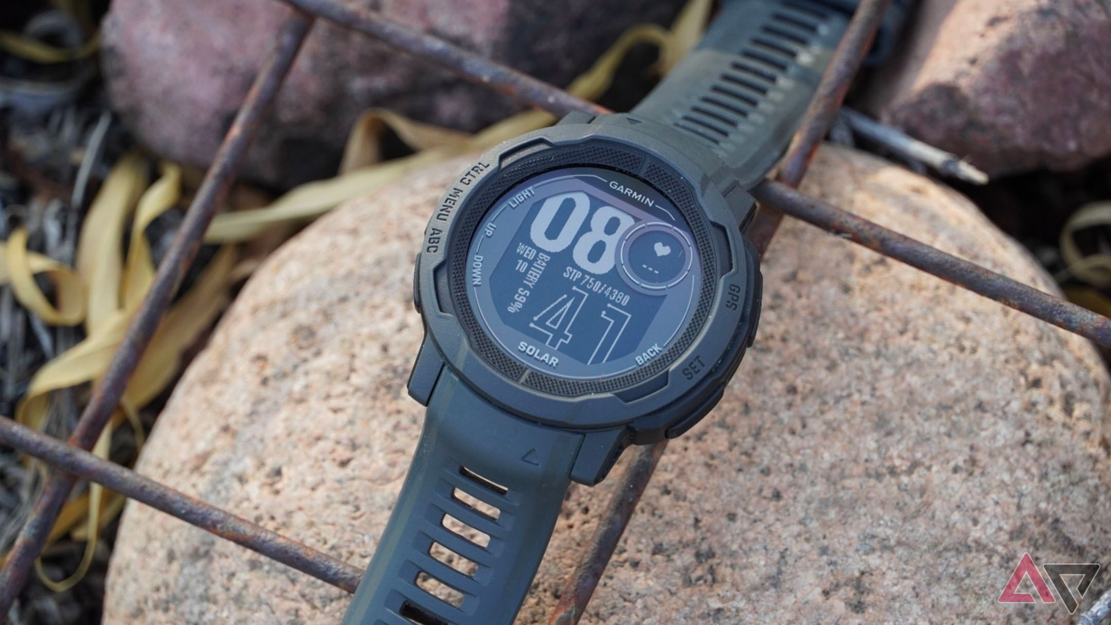 The Garmin Instinct 2 Solar lying on rocks.