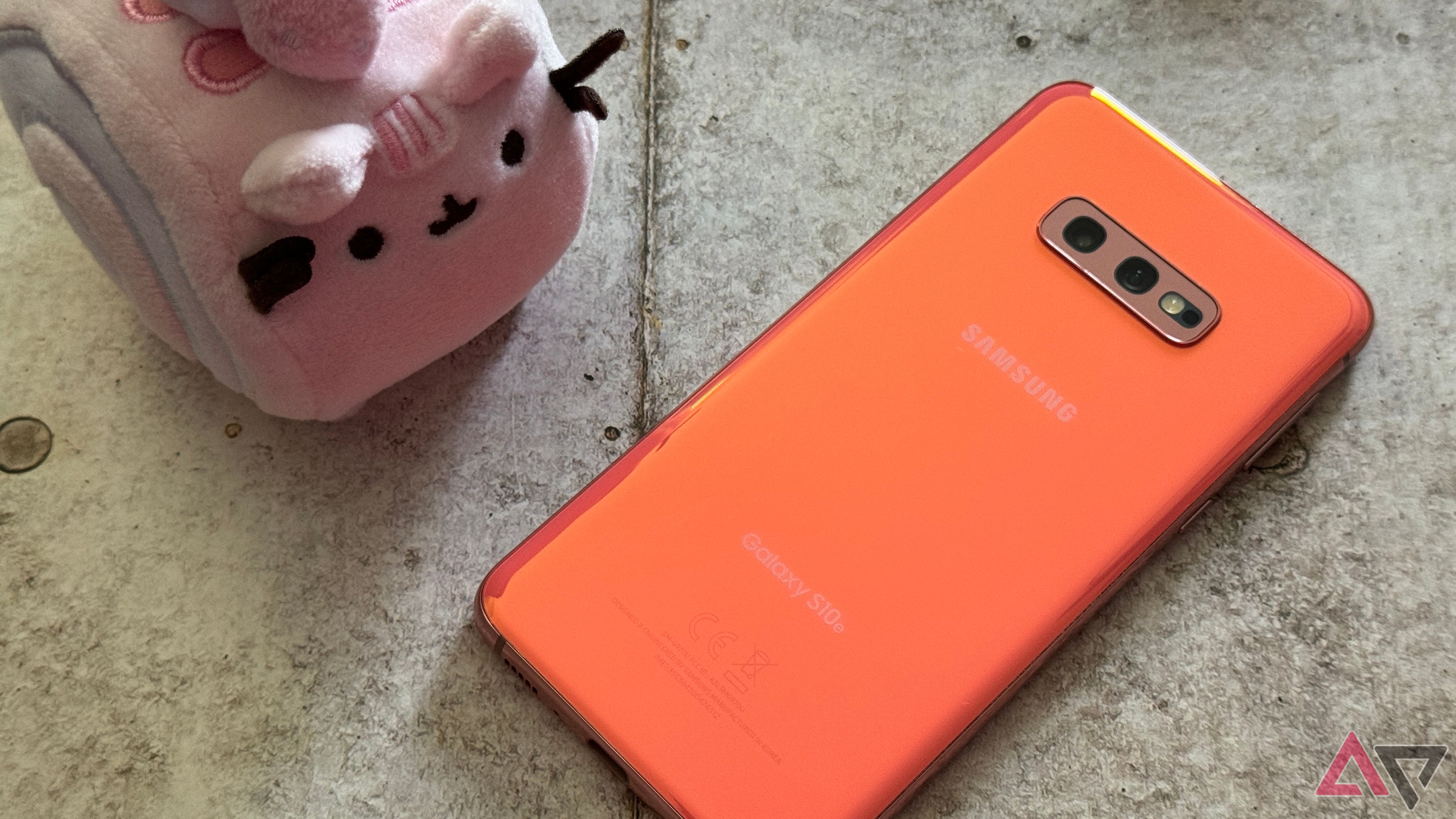 Samsung Galaxy S10e in Flamingo Pink sitting next to a Pusheen