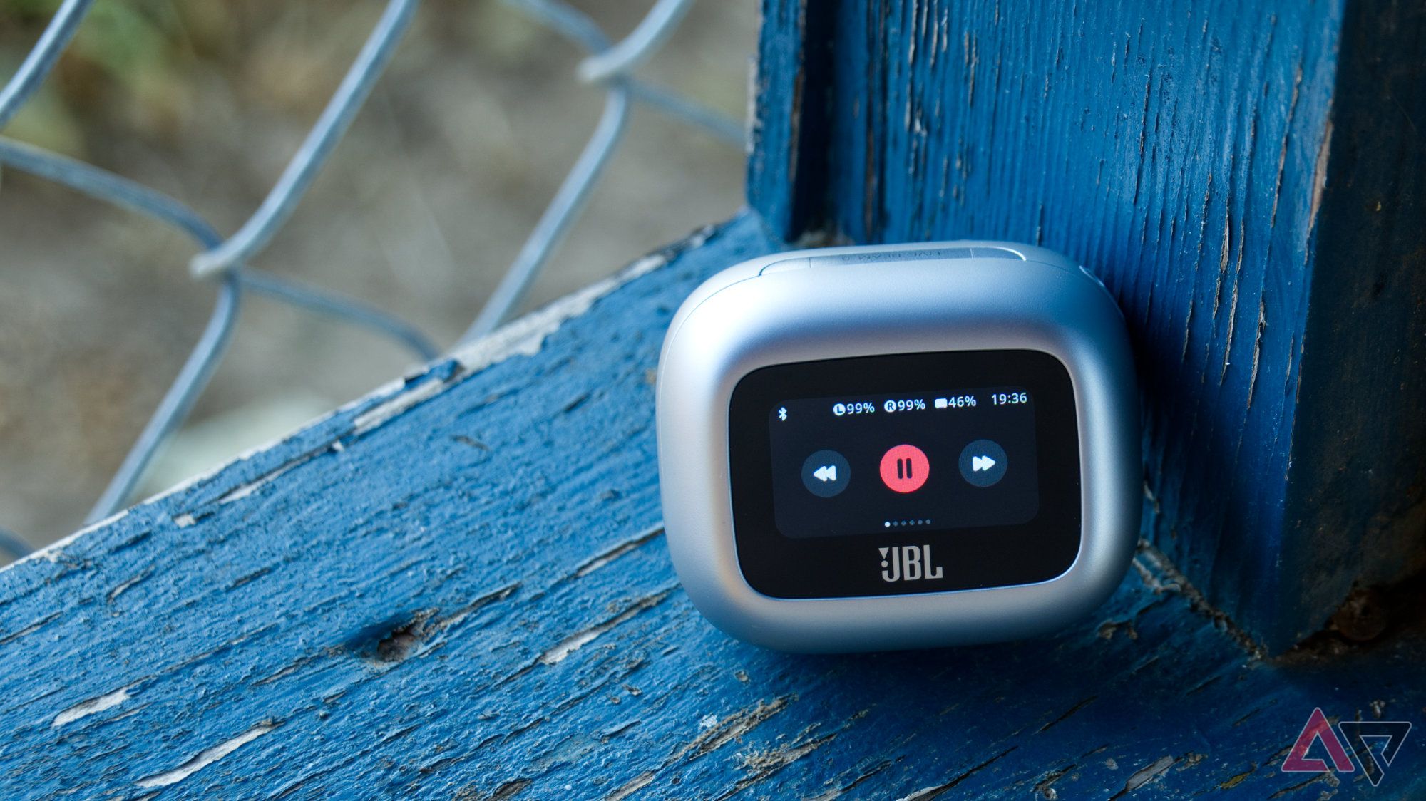 JBL Live Beam 3 case with the player controls on screen and resting on a wooden rail with chipped blue paint