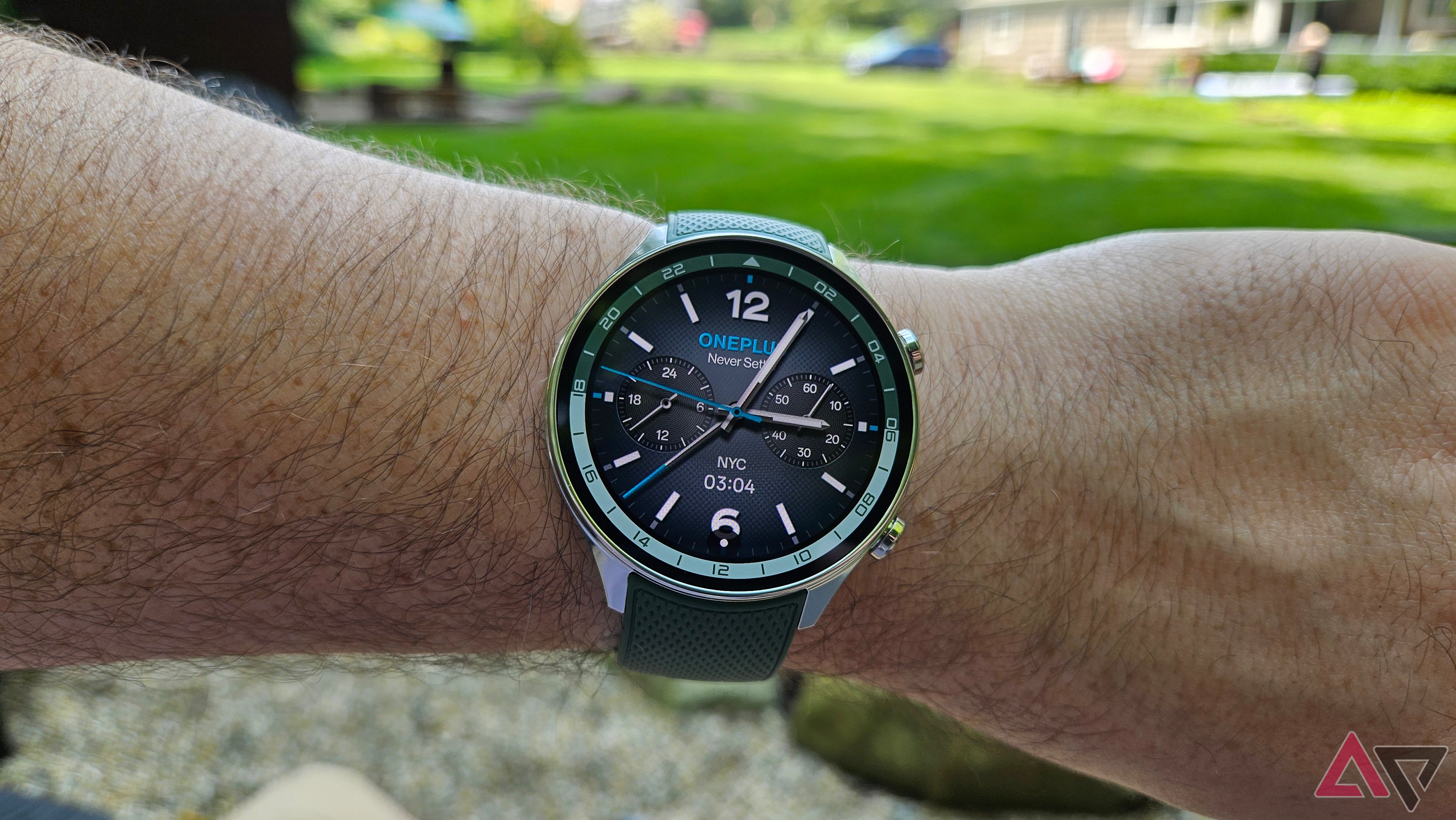 OnePlus Watch 2R worn on a wrist with green grass in the background