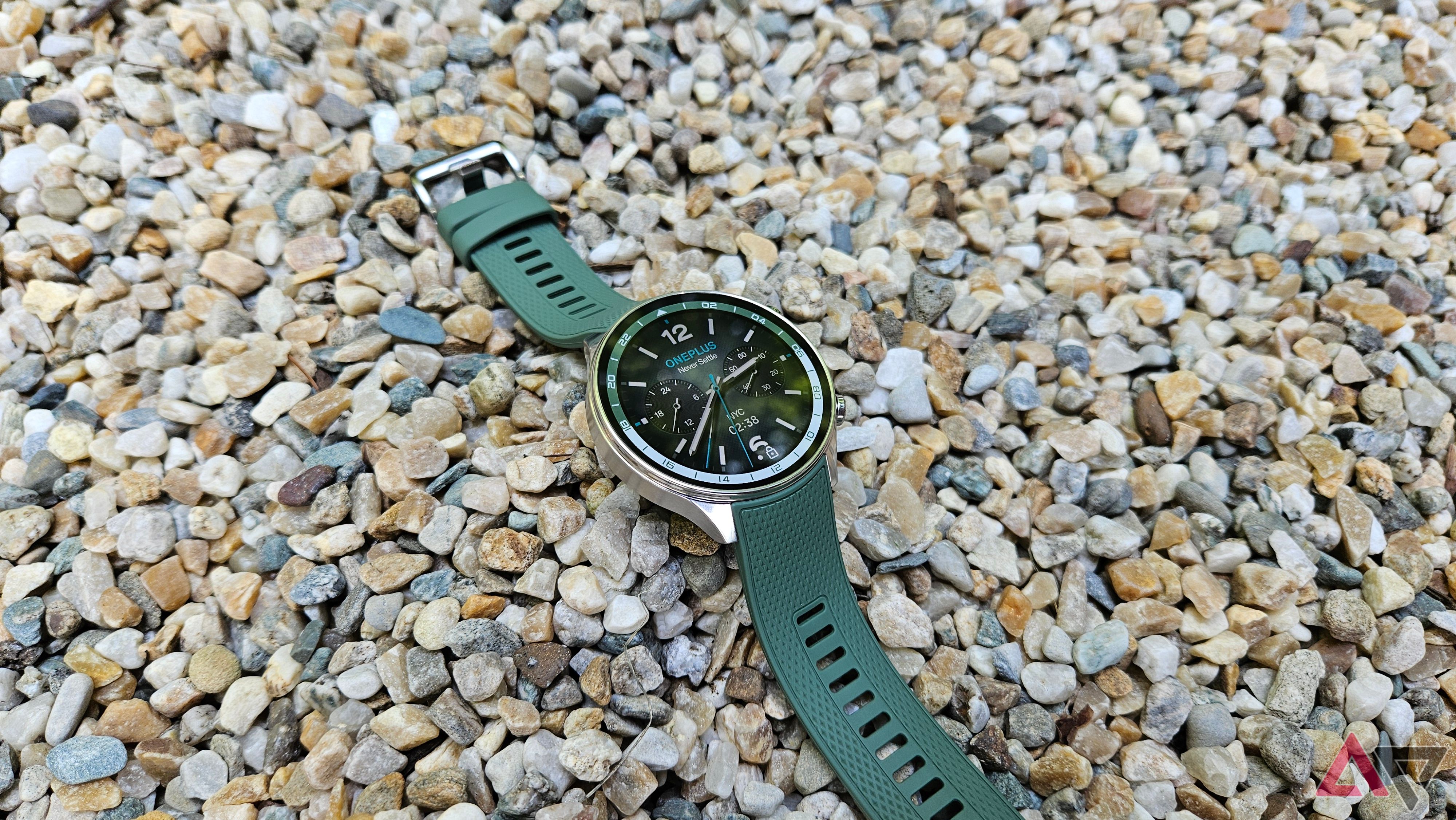 OnePlus Watch 2R Watch with its Forest Green strap on pebbles