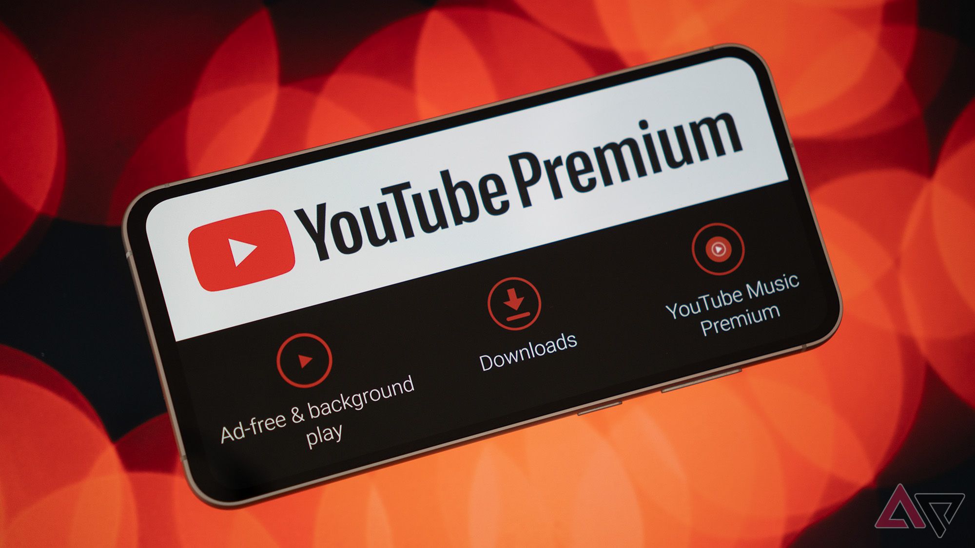 Mobile phone with YouTube Premium logo and features on red bokeh background.