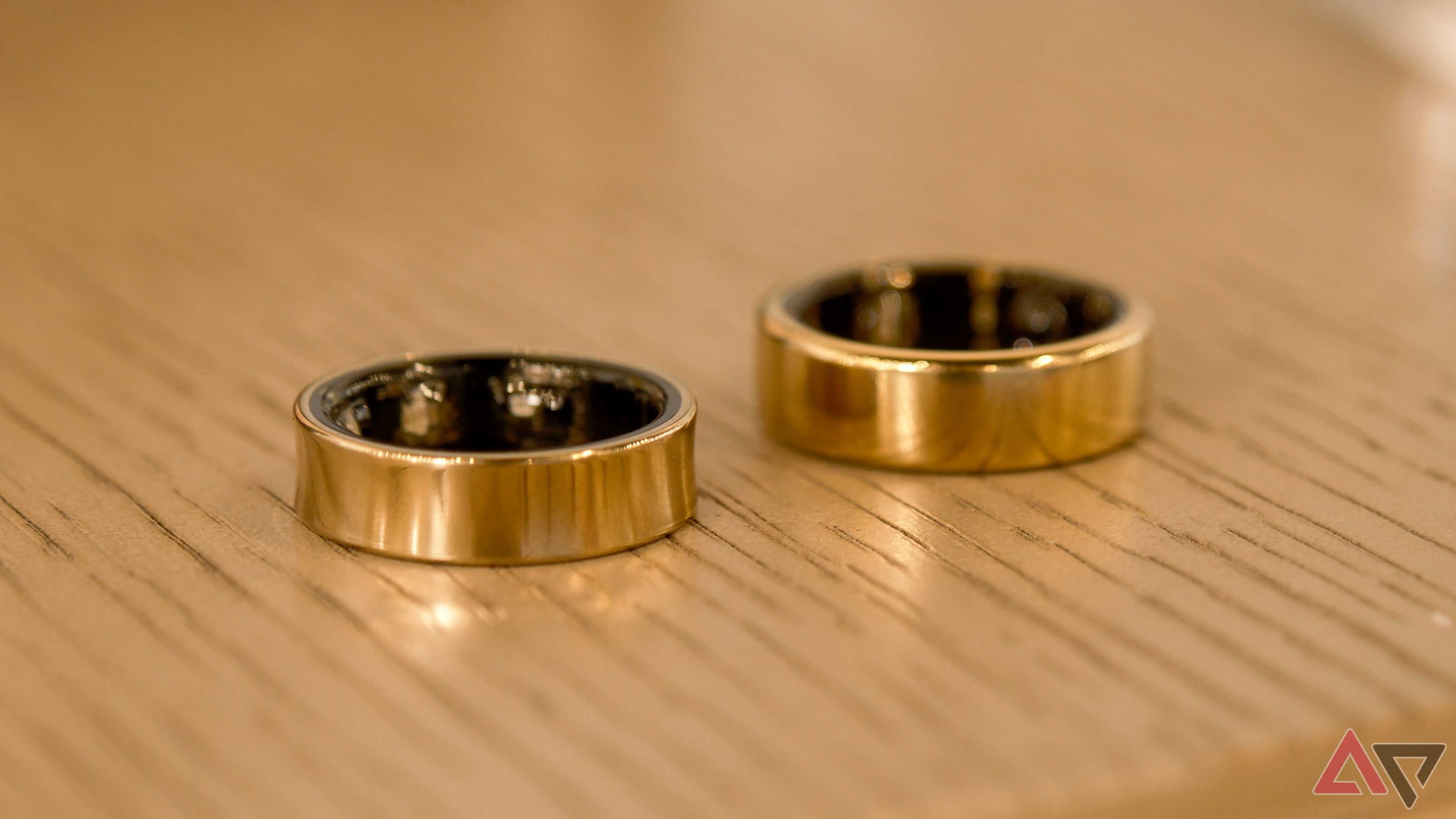 The Samsung Galaxy Ring and Oura Ring side-by-side on wood surface