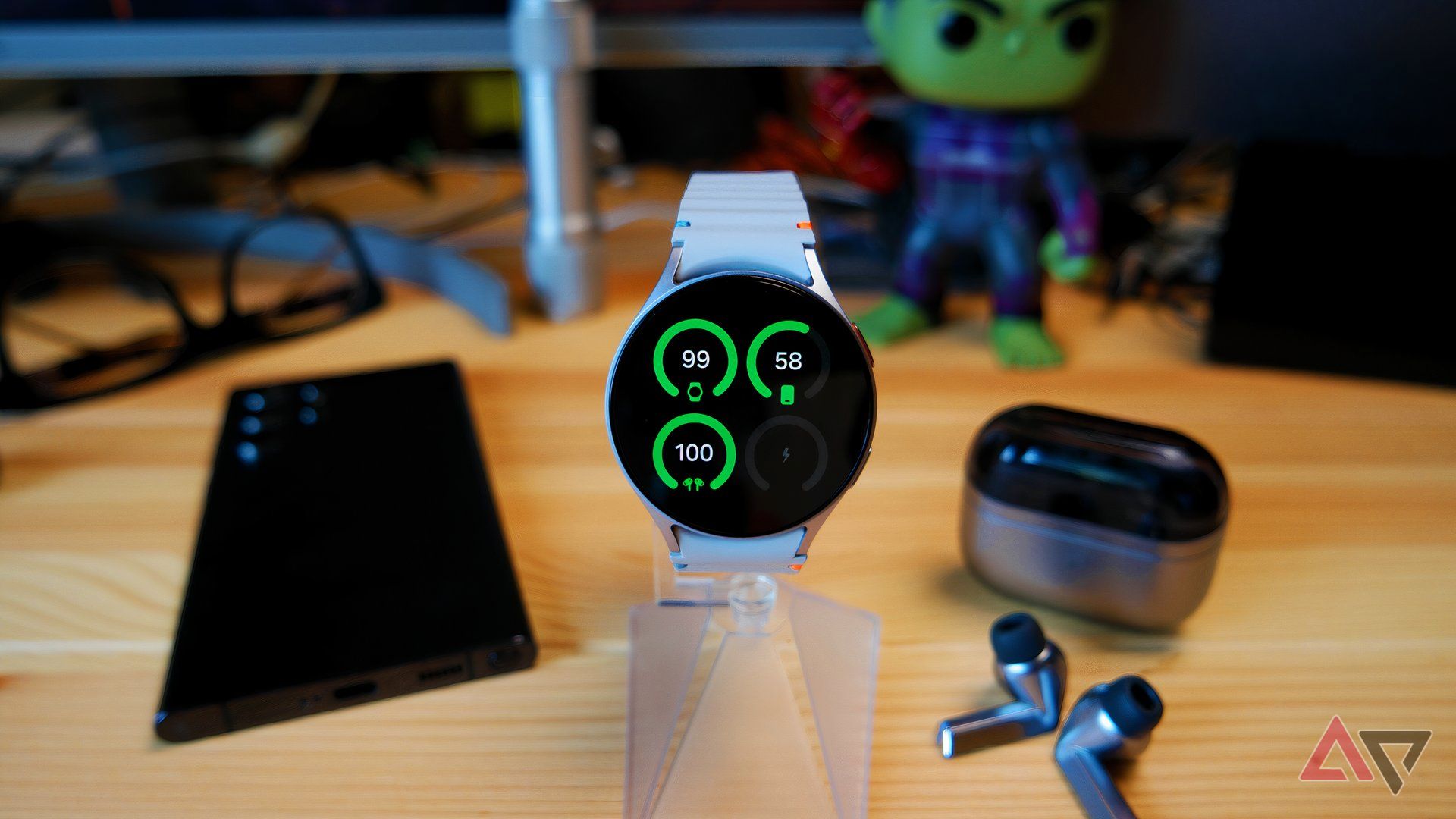 Samsung Galaxy Watch 7 on a watch stand showing battery widget info