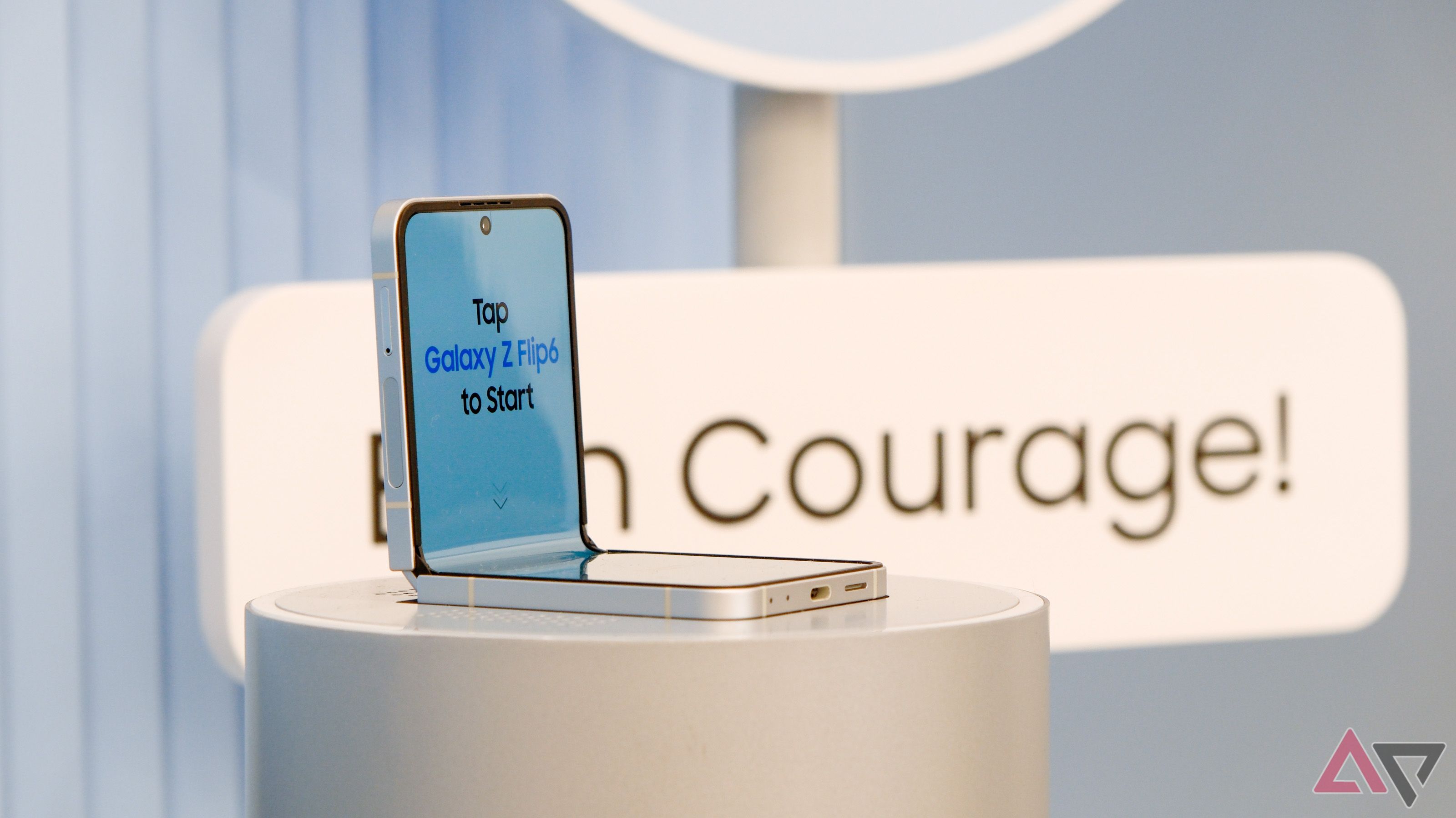 A Samsung Galaxy Z Flip 6 in front of a sign that says "Courage"