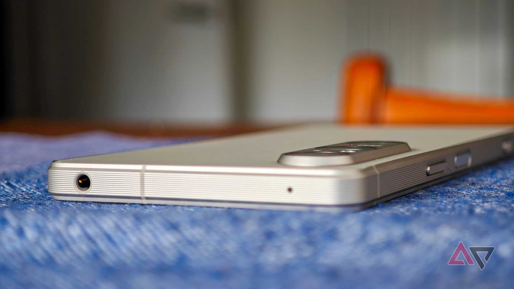 A photo of the Sony Xperia 1 VI resting on a blue tablecloth, showing the headphone jack