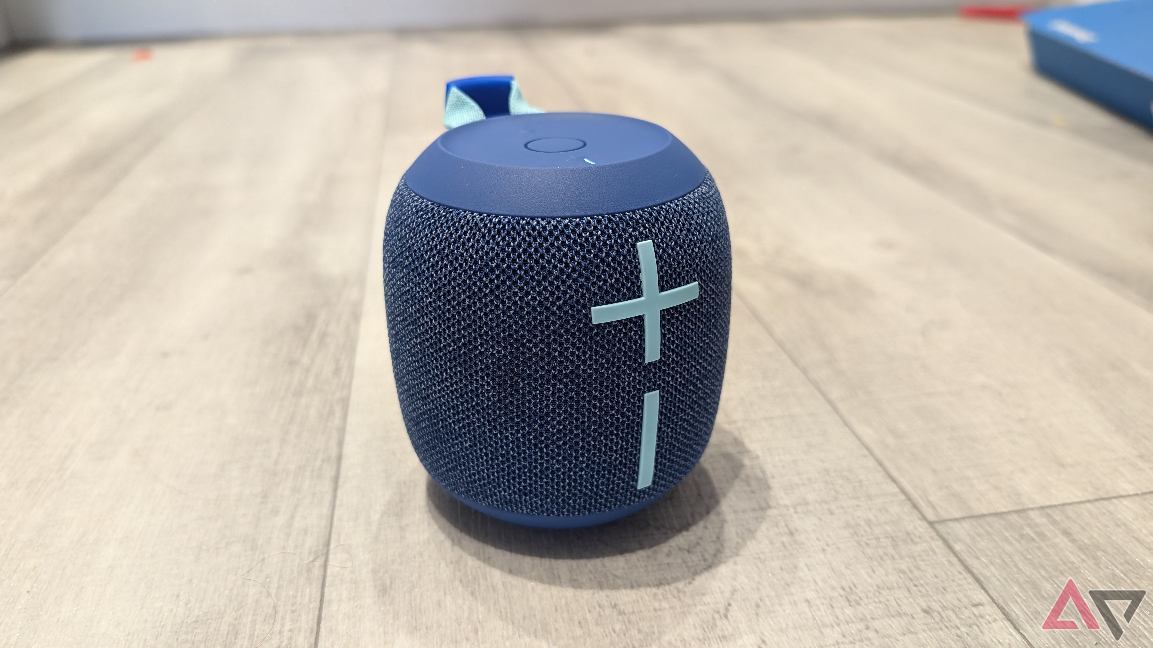 blue bluetooth speaker on pale wood floor