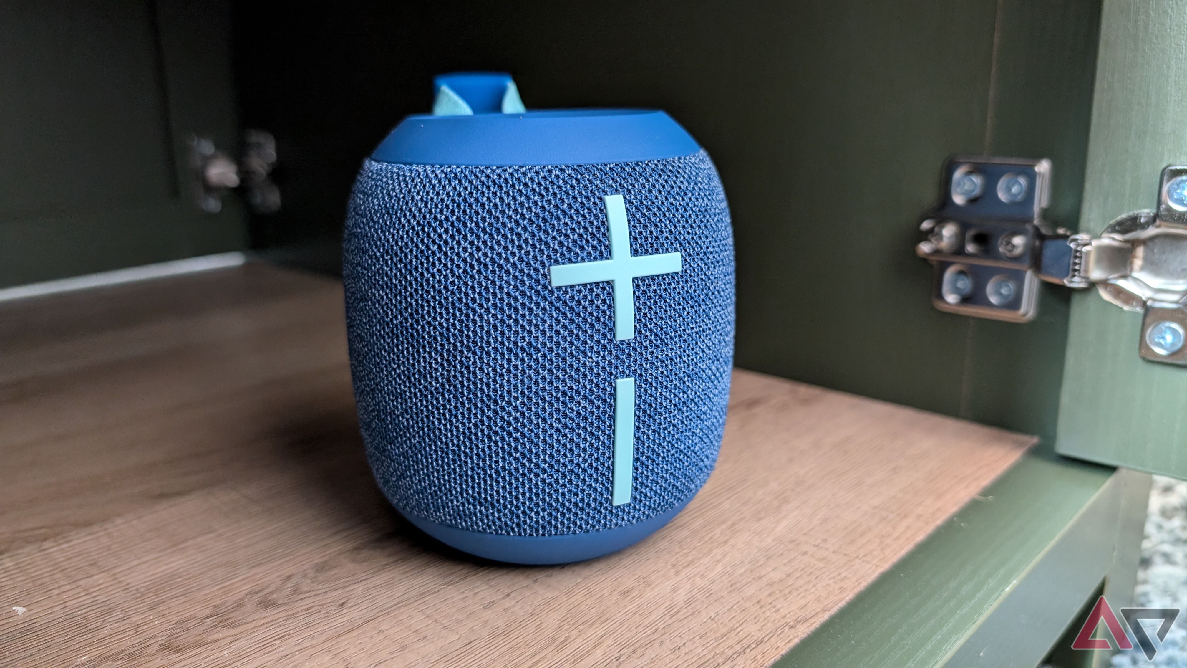 blue bluetooth speaker on wood and green cabinet