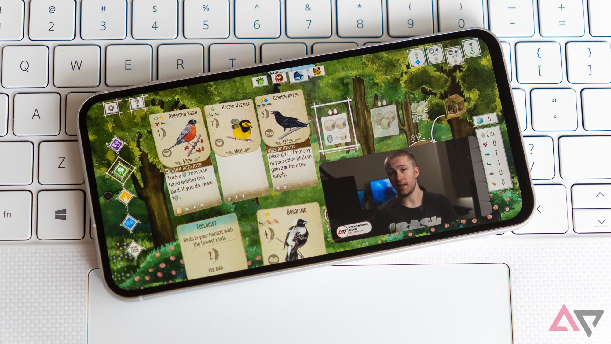 A Game And Video Playing Simultaneously On A Samsung Phone On A White Laptop Keyboard 