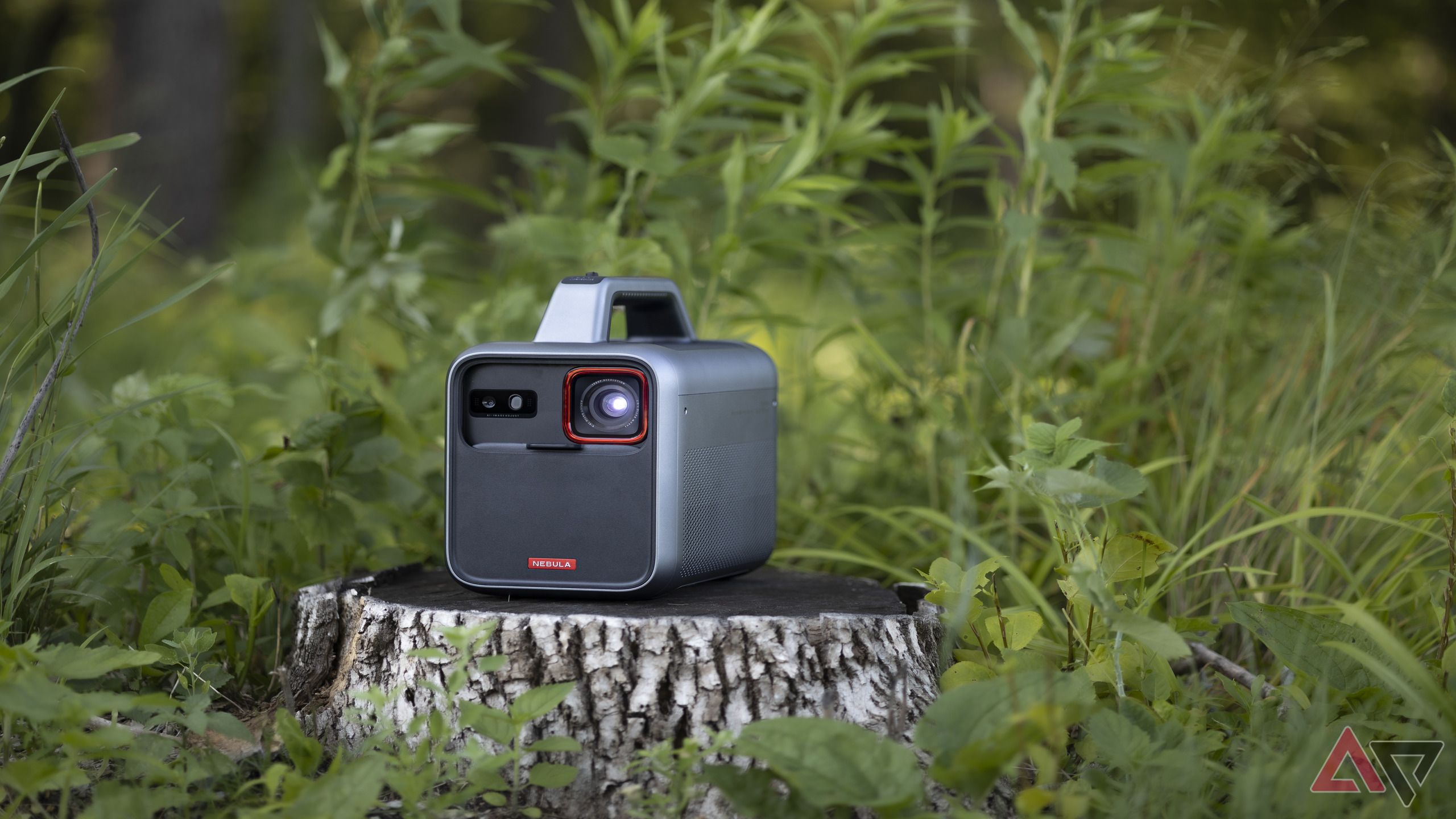 Anker Nebula Mars 3 projector on tree stump in grassy area