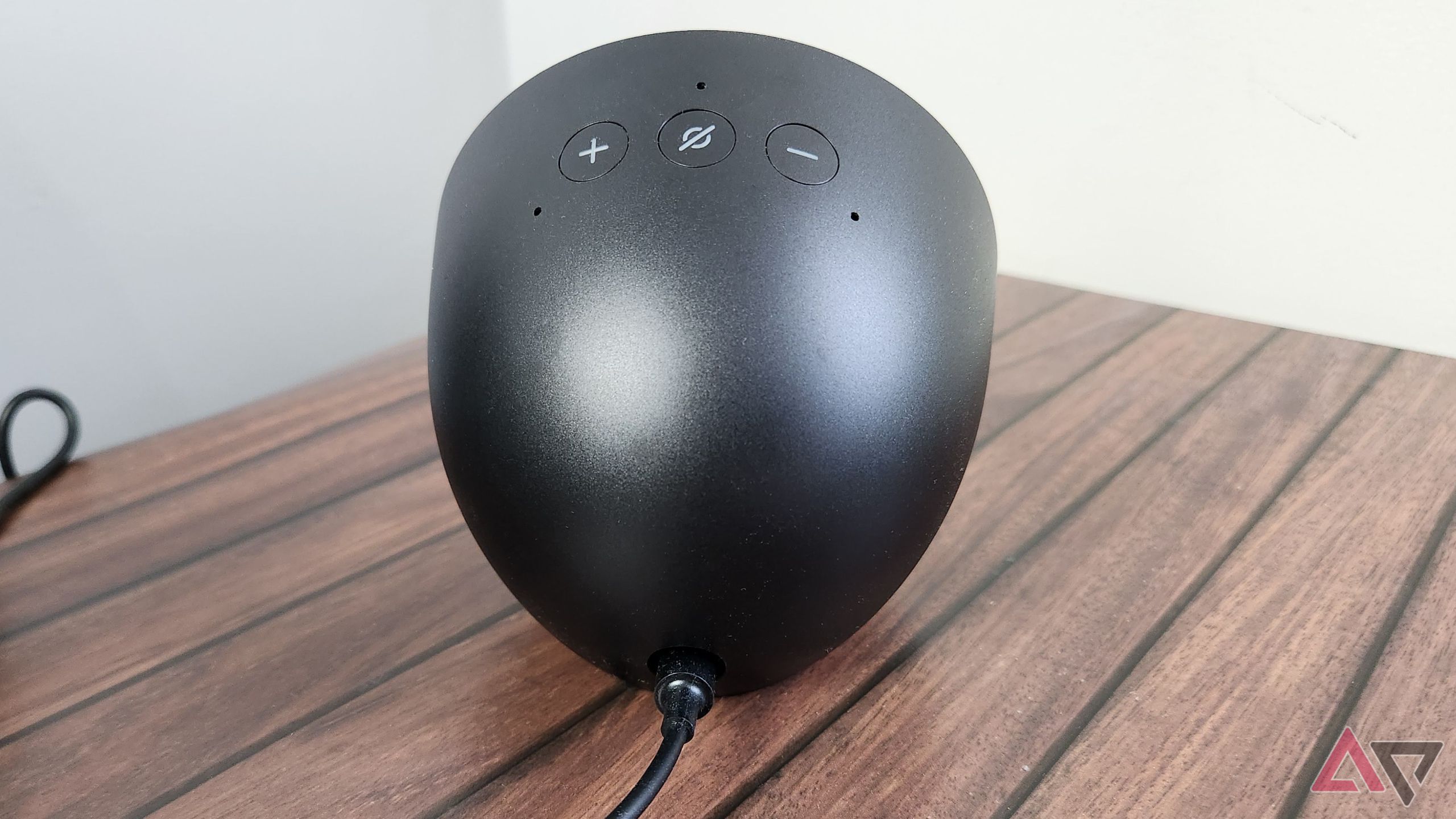 The back of the Amazon Echo Spot on a wooden table showing the three buttons and cable