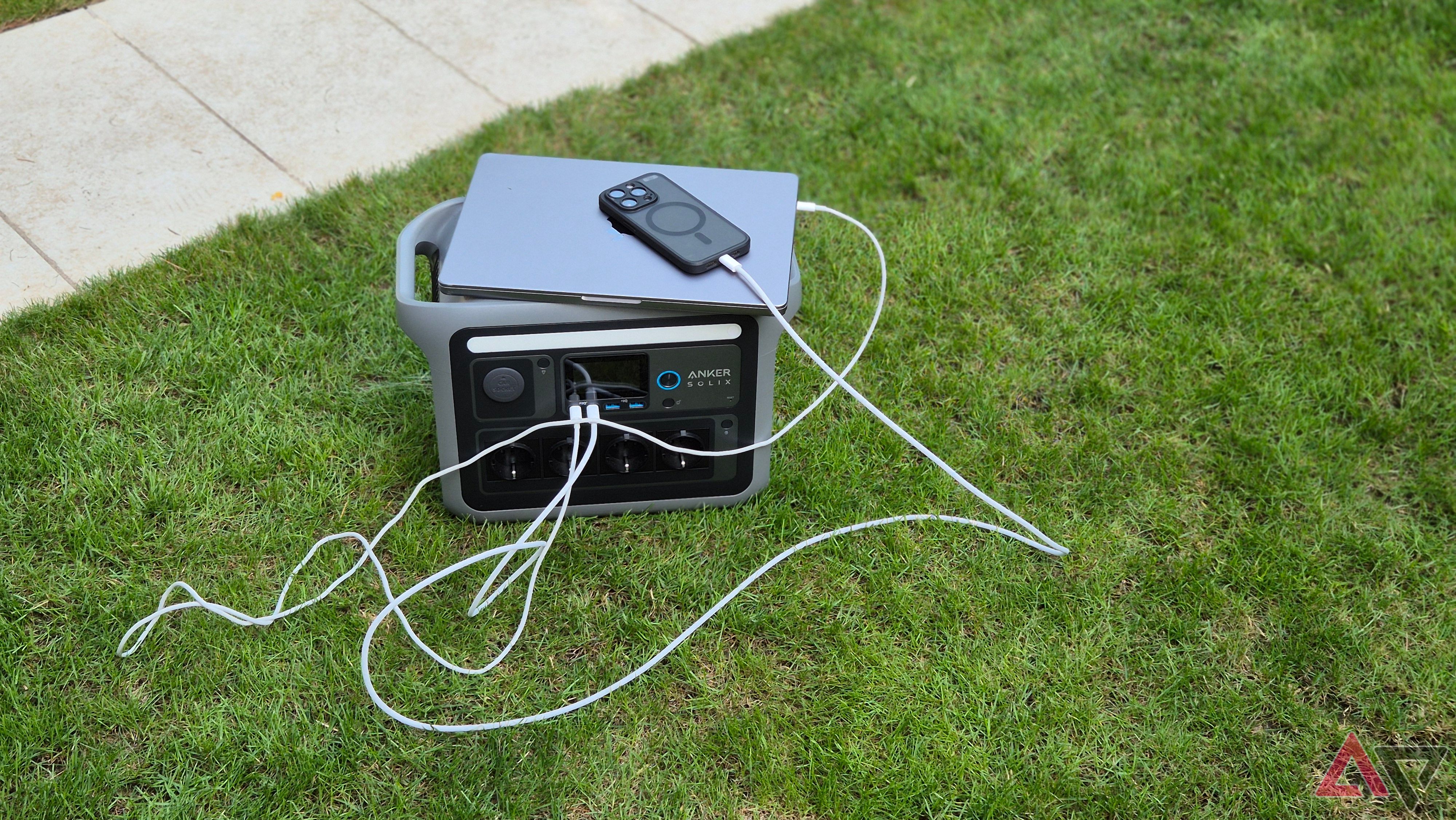 A MacBook Pro and an iPhone 15 Pro plugged into the Anker Solix C1000 portable battery station