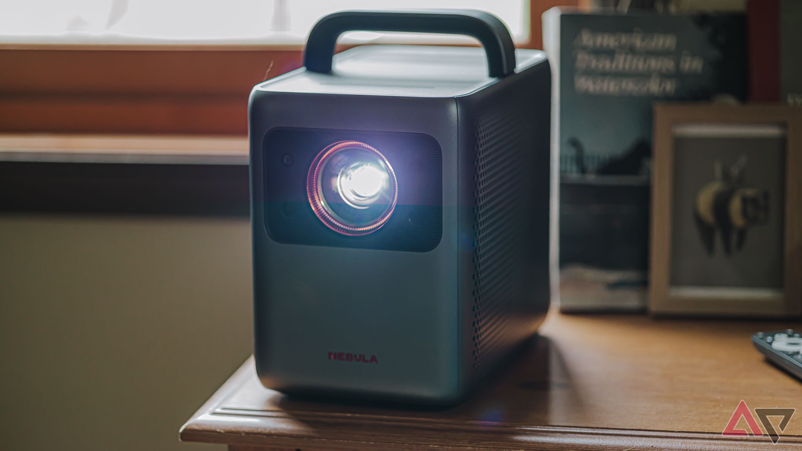 Anker Nebula Cosmos 4K projector with lamp sitting on a wooden table