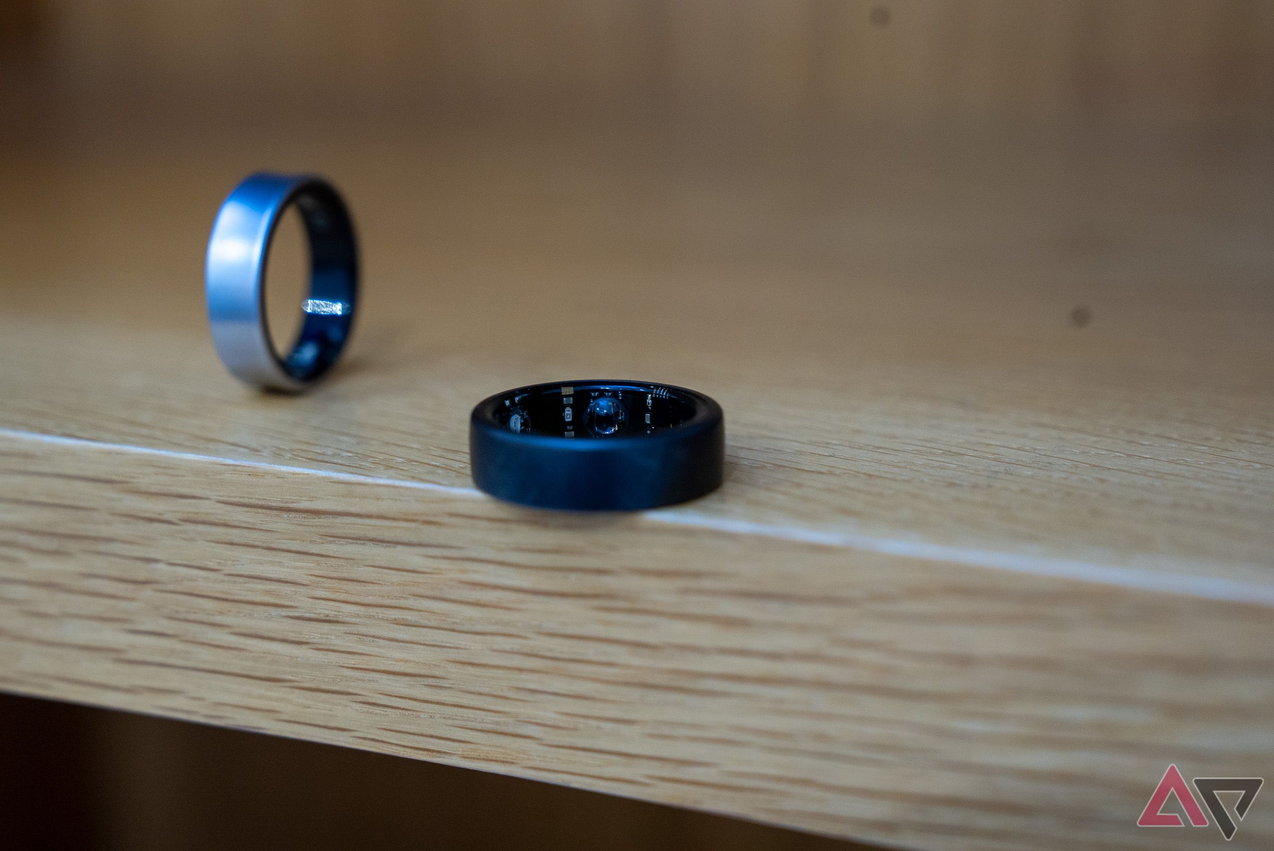 Oura Ring flat on a shelf next to an upright Galaxy Ring