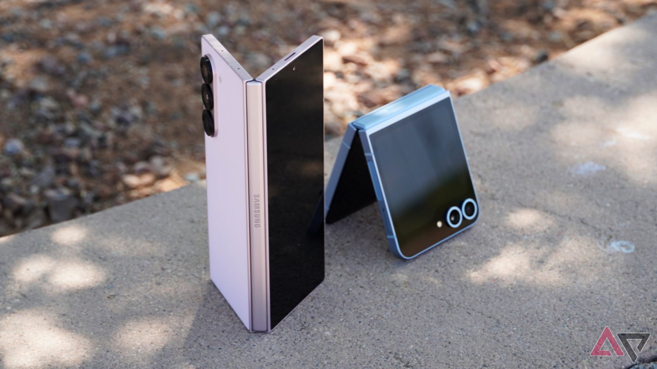 The Galaxy Z Flip 6 and Z Fold 6 half-opened on a concrete ledge outside.