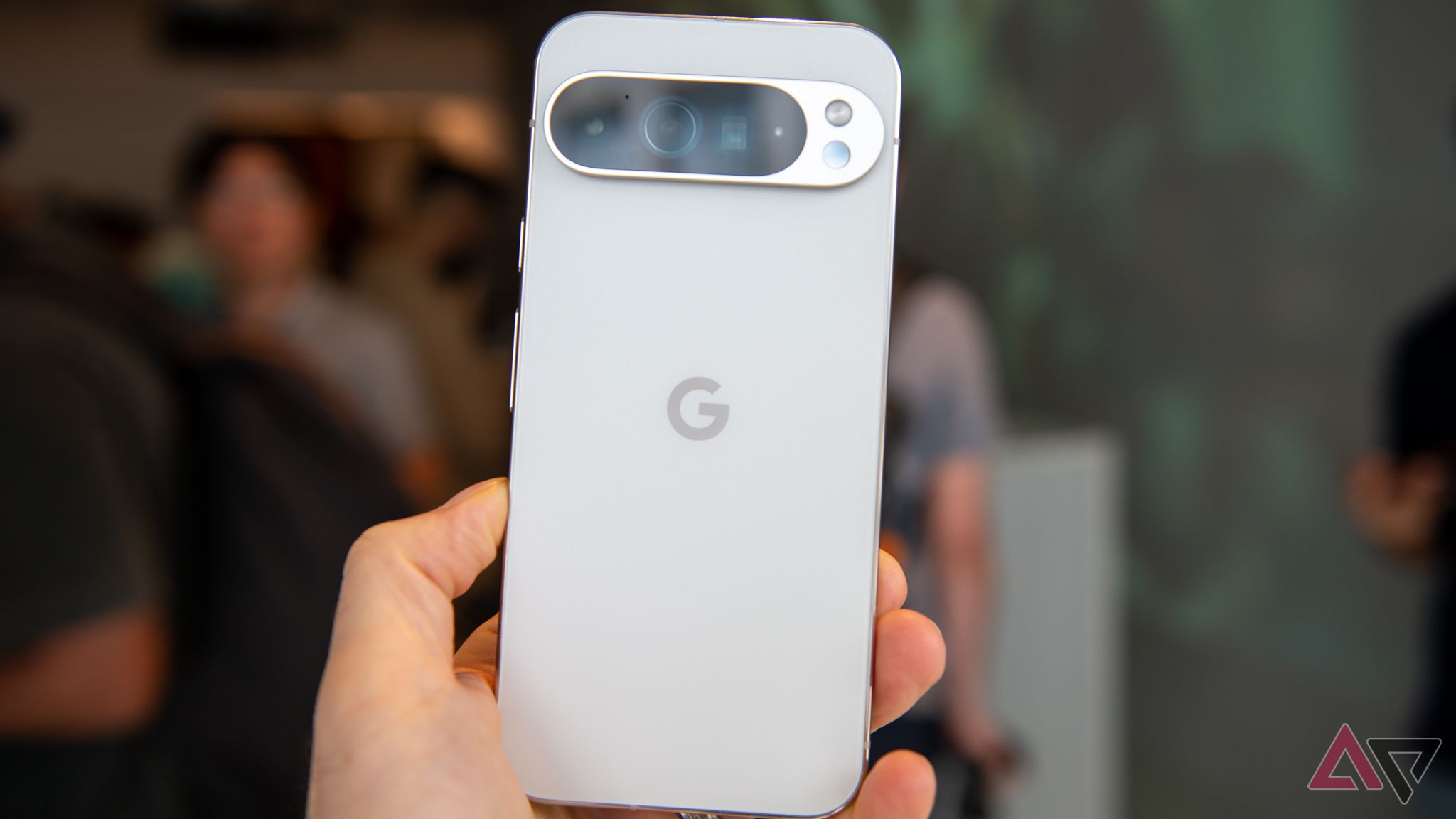 A hand holding a Google Pixel 9 Pro showing the cameras on the back