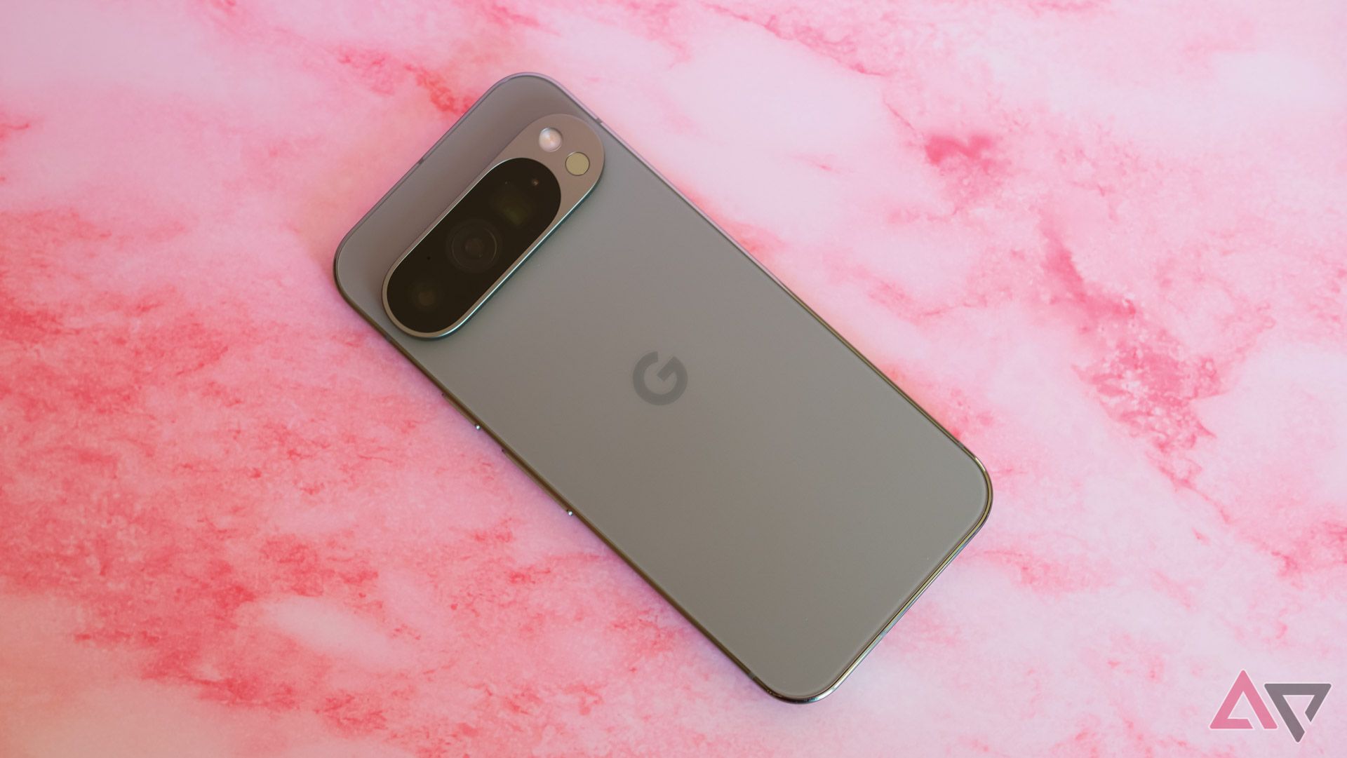 The Pixel 9 Pro on a pink backdrop shot from the top down with the display facing down.