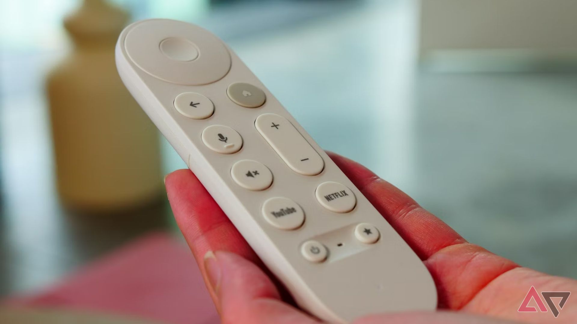 A hand holding a Google TV Streamer remote controller