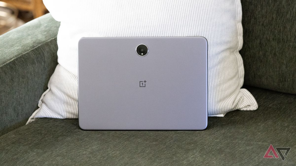 The back of a OnePlus Pad 2 while propped up on a green couch and striped pillow