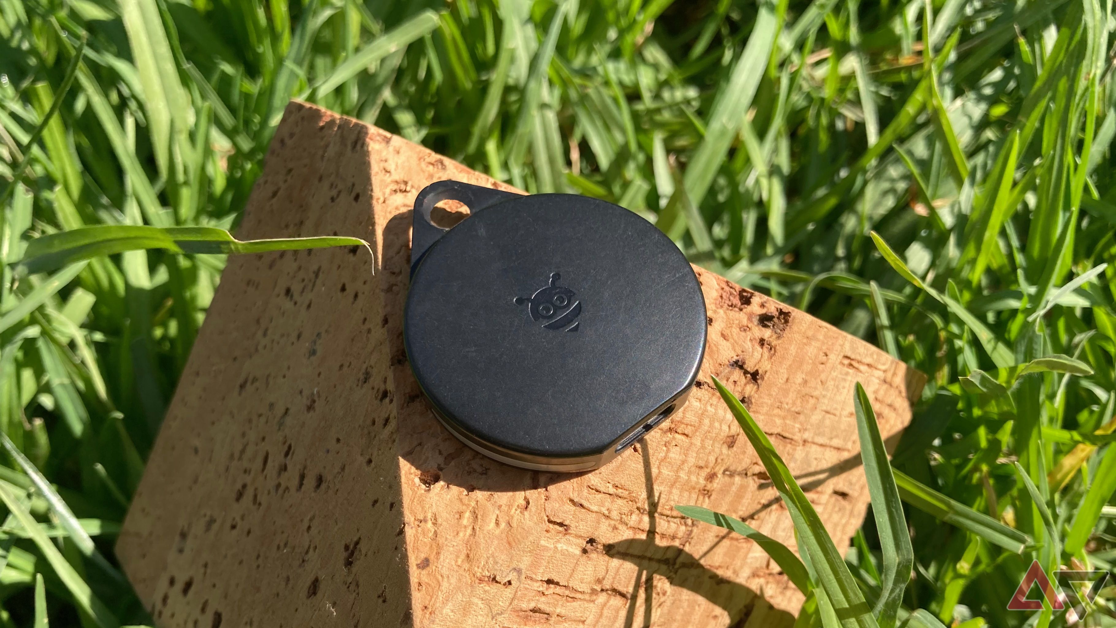 The Pebblebee Clip for Android sitting on the corner of an angular, shaped piece of cork