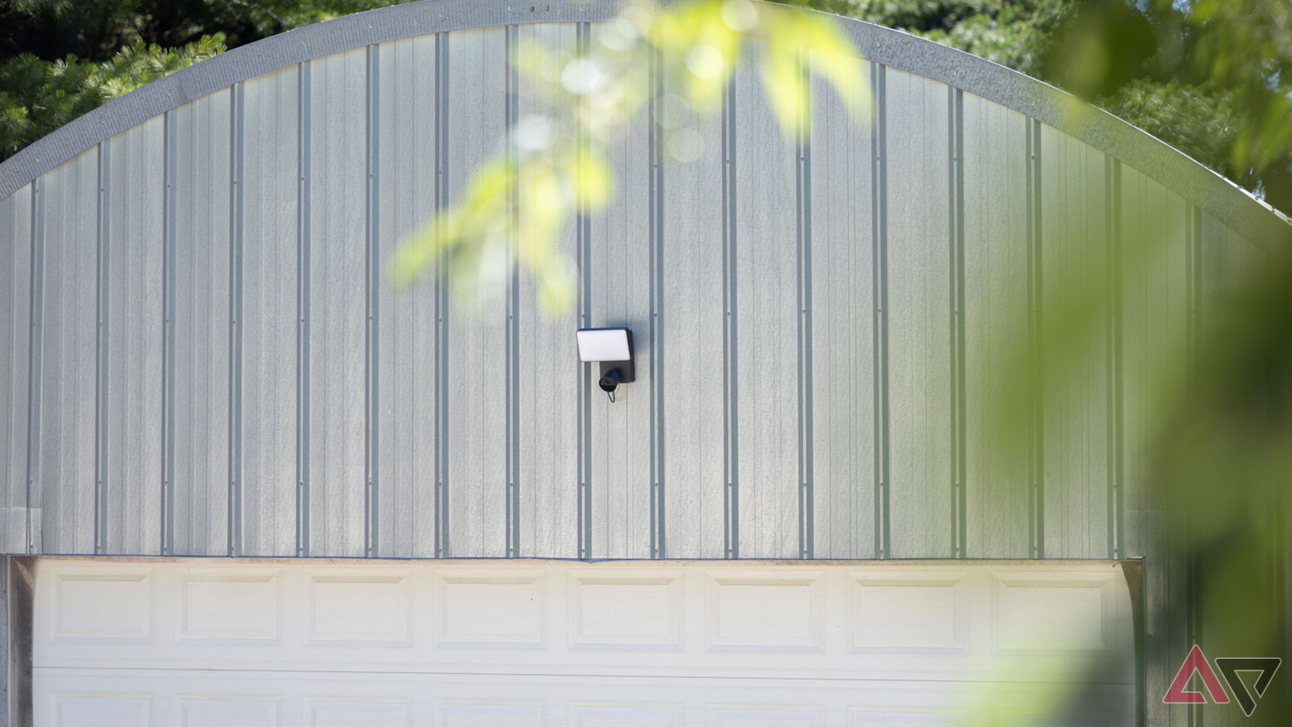 Distant view of Philips Hue Secure Floodlight Camera mounted on metal quonset