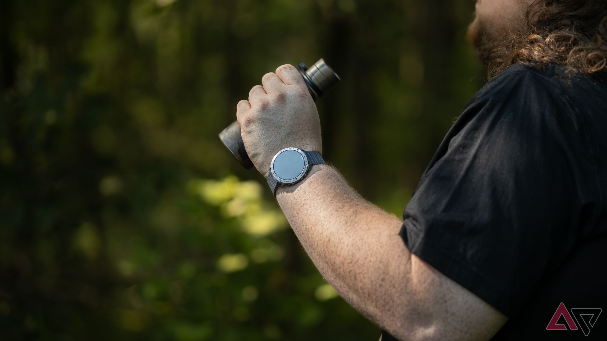 Man wearing Polar Grit X2 Pro smartwatch and using binoculars