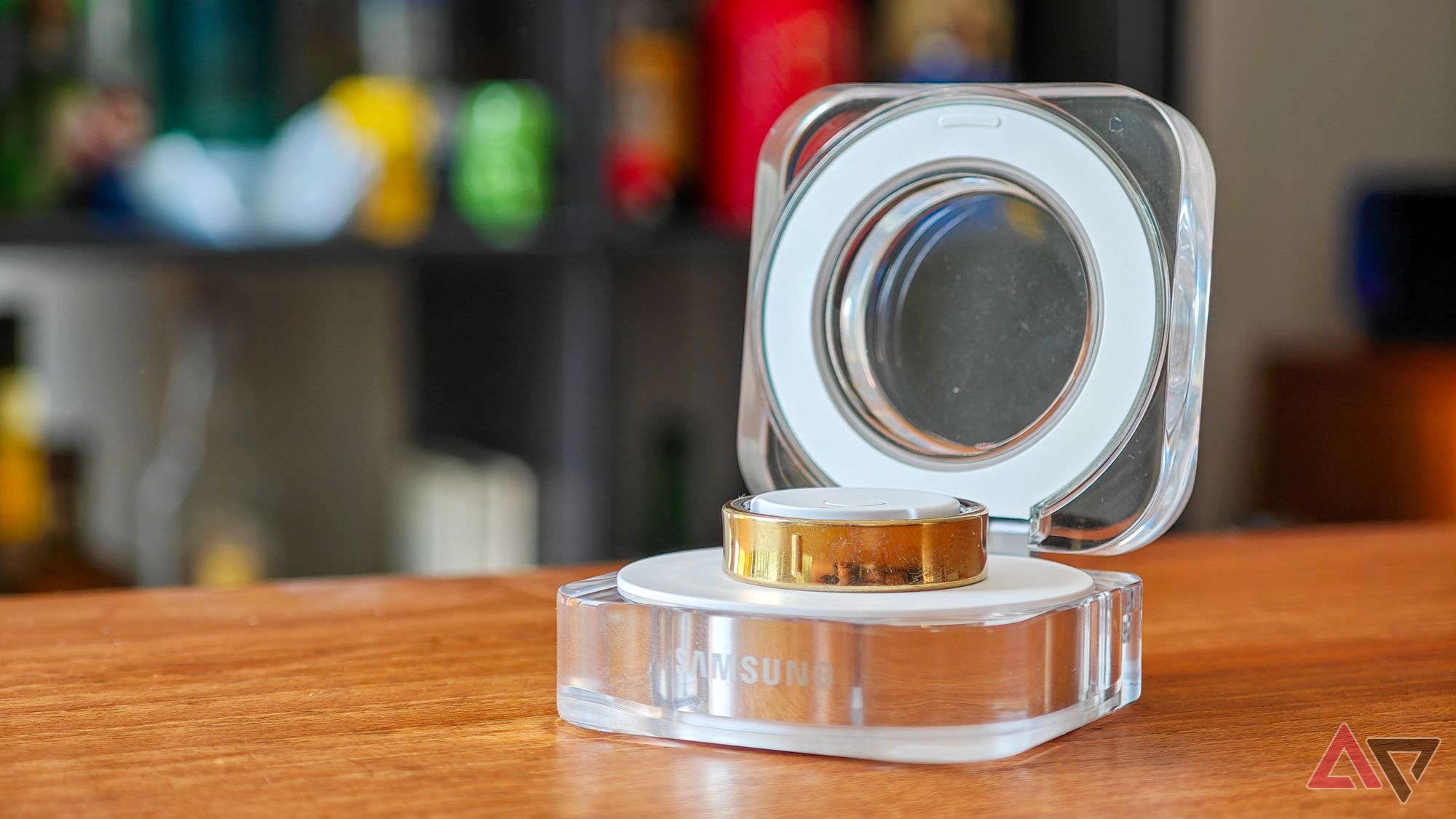 A gold Samsung Galaxy Ring resting in an open charging case on a wooden table