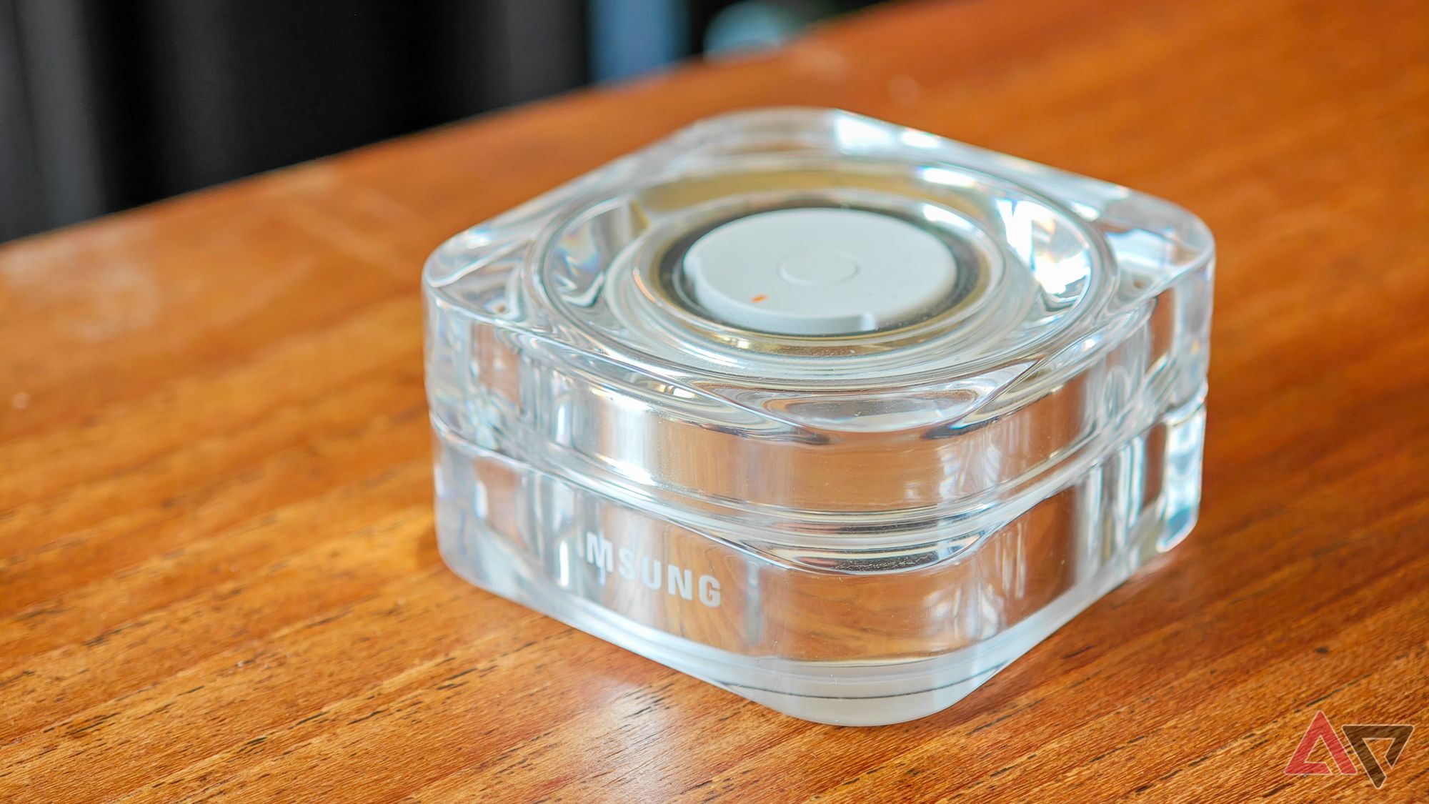 A gold Samsung Galaxy Ring in a closed charging case on a wooden table