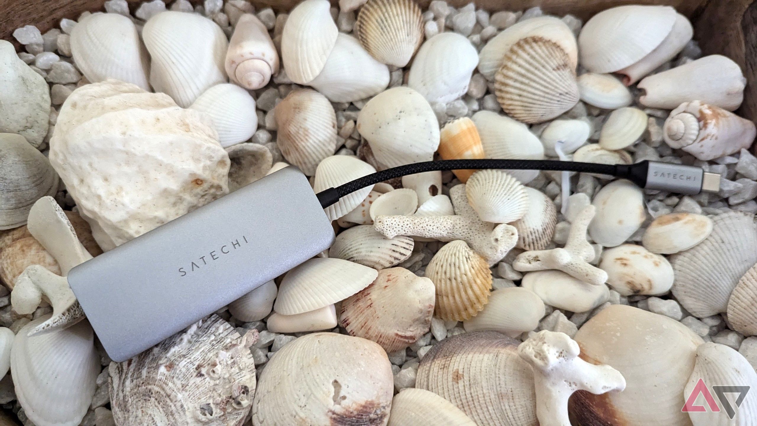 silver-gray USB hub with shells in the background