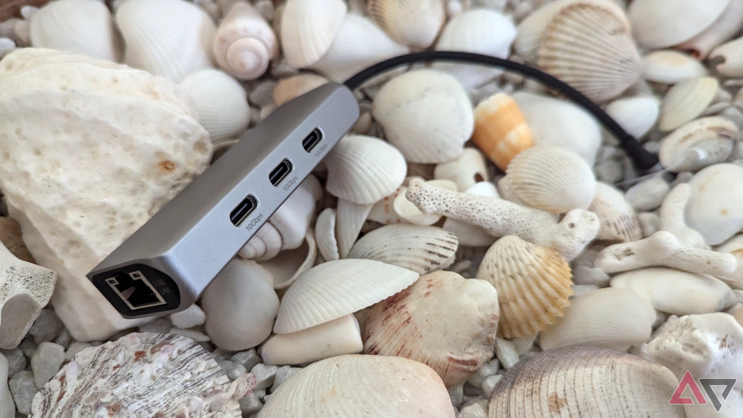 lifestyle shot of the silver-gray USB hub with shells in the background