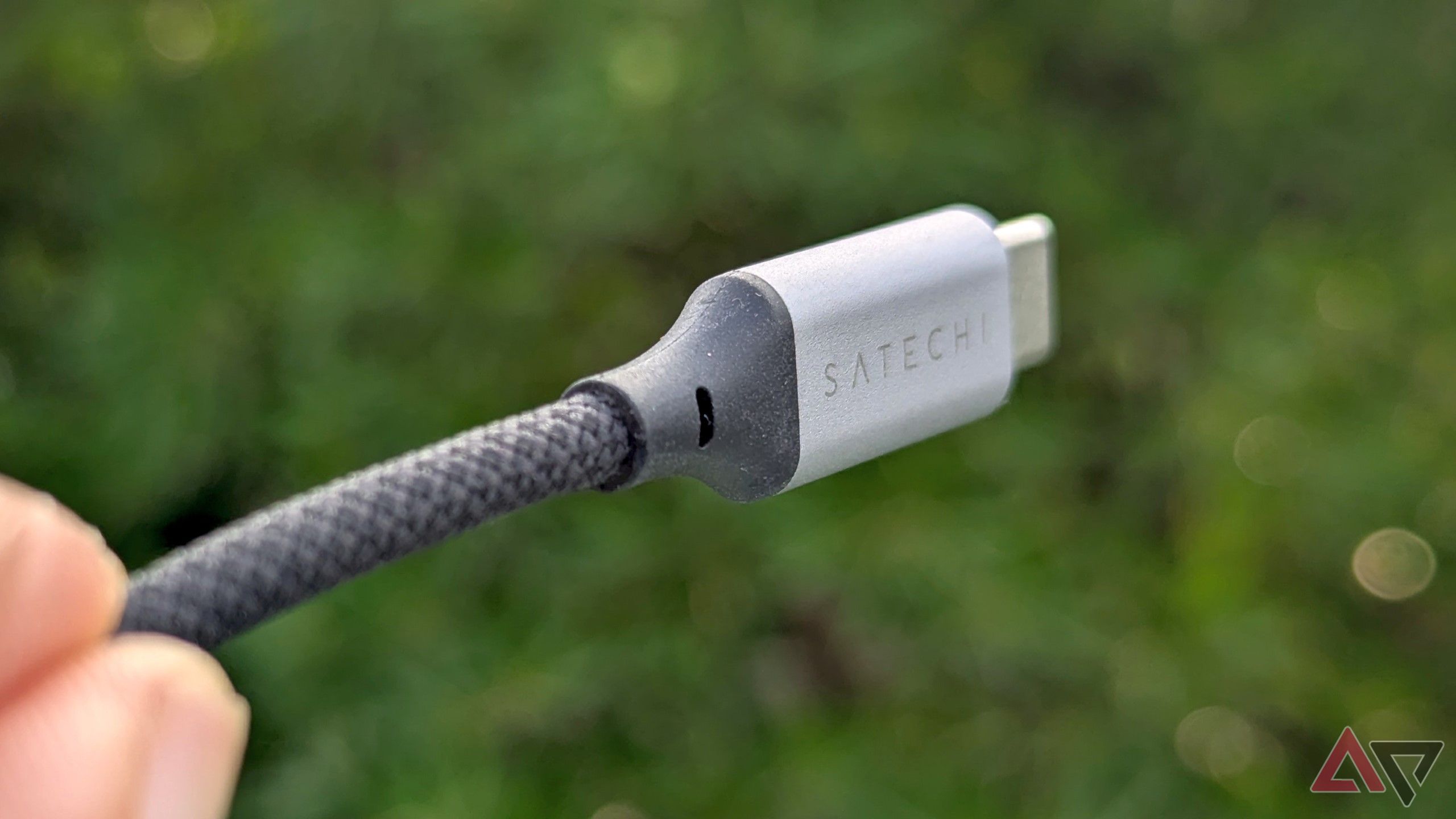 thick braided cable of the silver-gray USB hub with a tree in the background