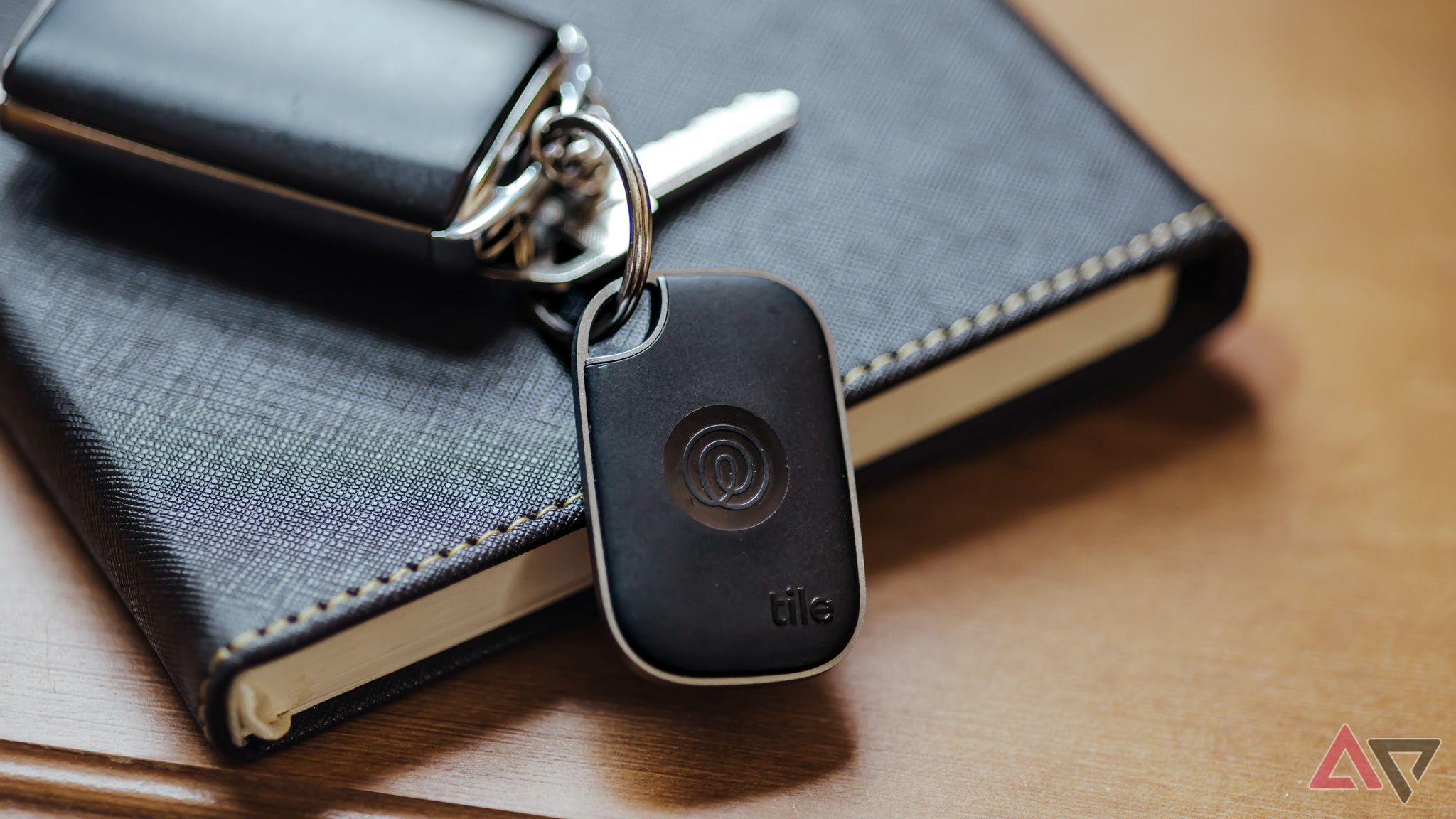 Tile Pro 2024 Bluetooth tracker on keyring with car keys, sitting on black leather notebook