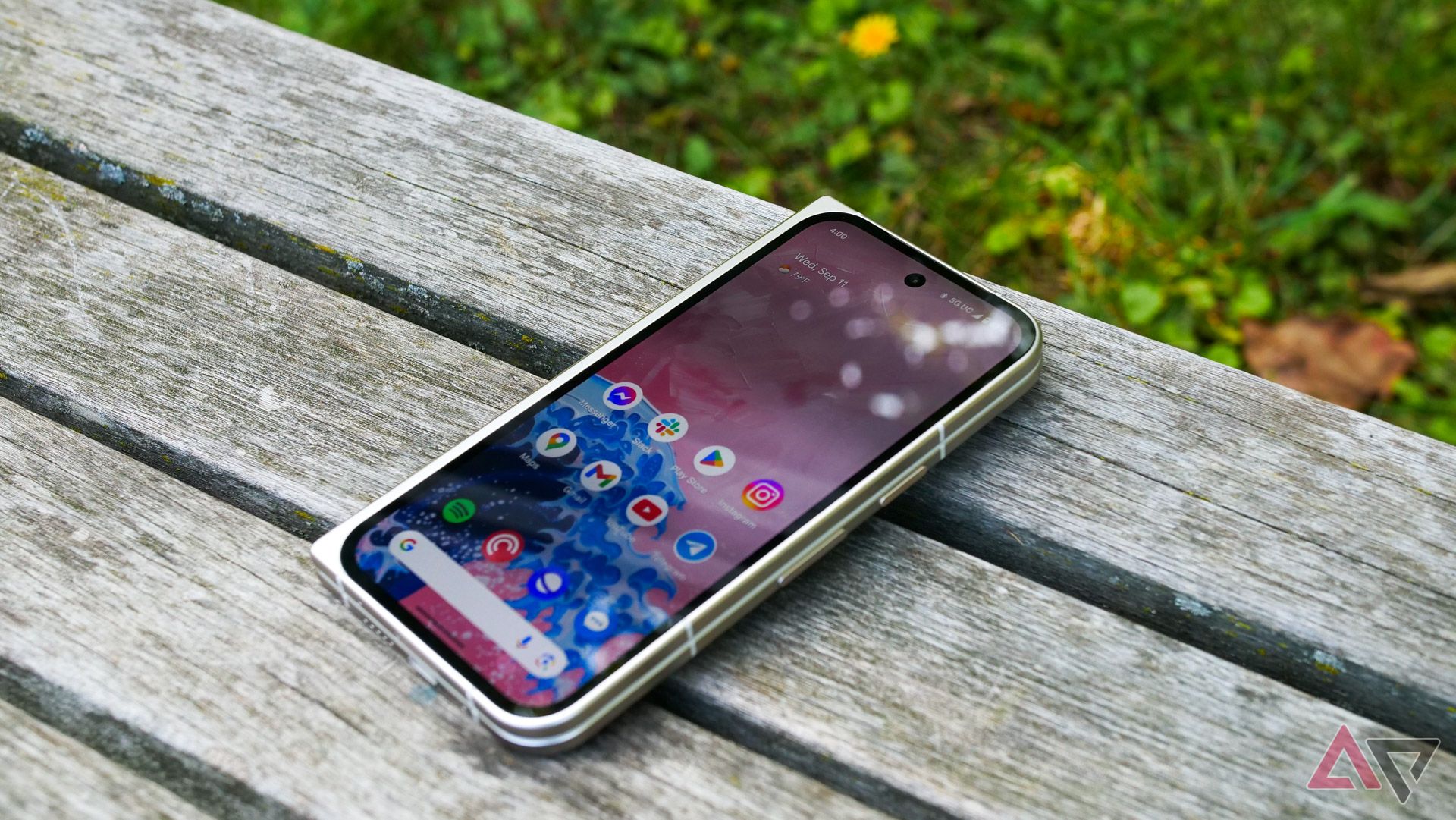 The Pixel 9 Pro Fold on a park bench with the display turned on.