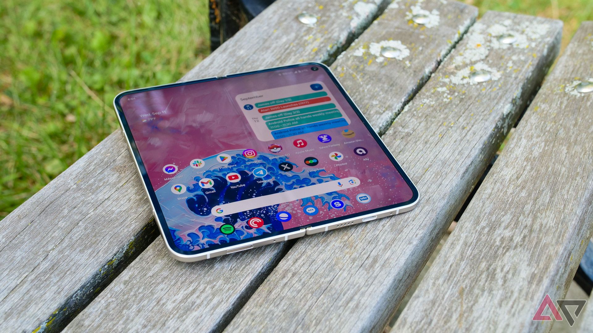 Pixel 9 Pro Fold di bangku taman dengan layar utama terbuka.