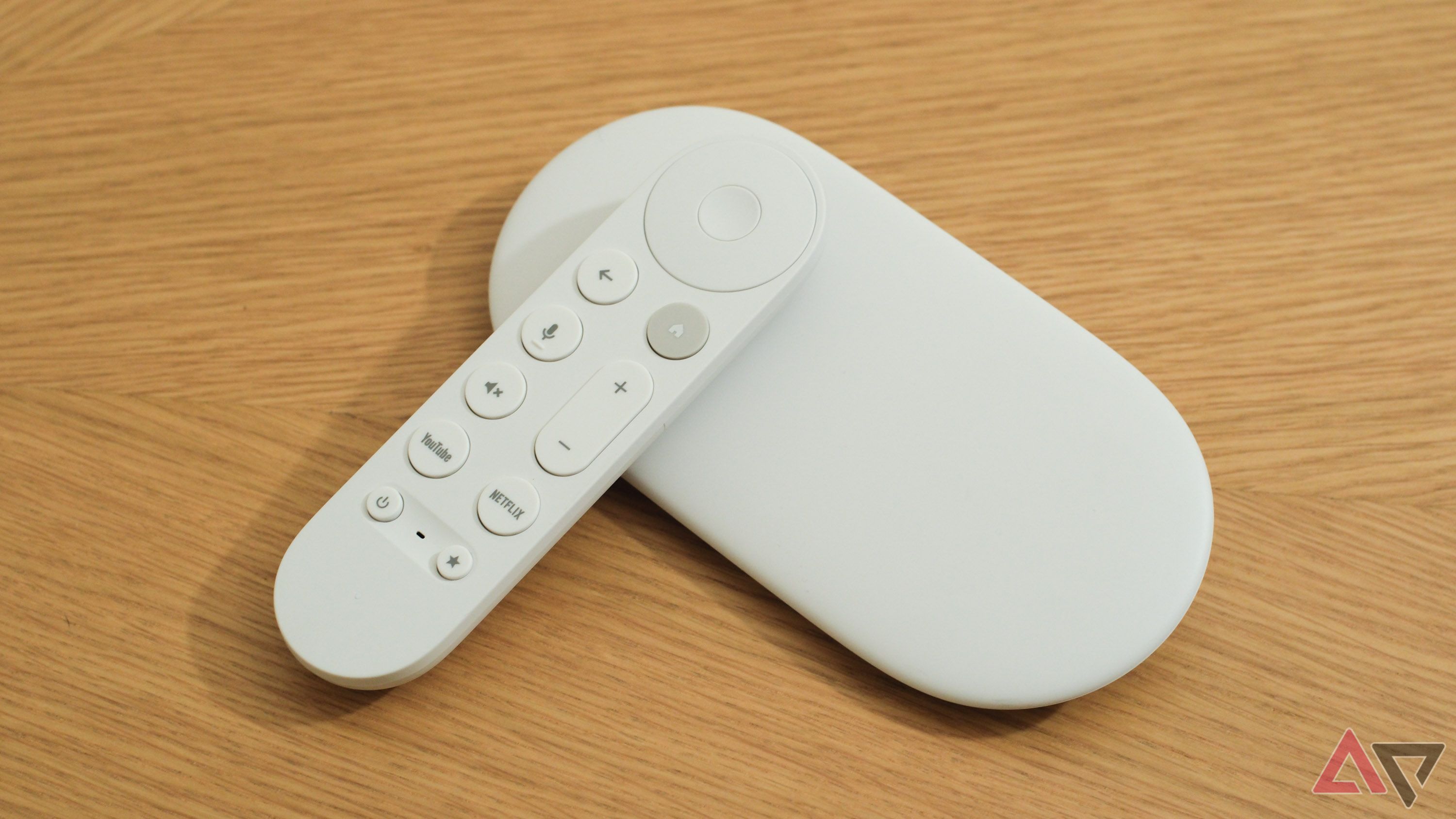 The Google TV Streamer with its remote leaning against it on a wooden surface.