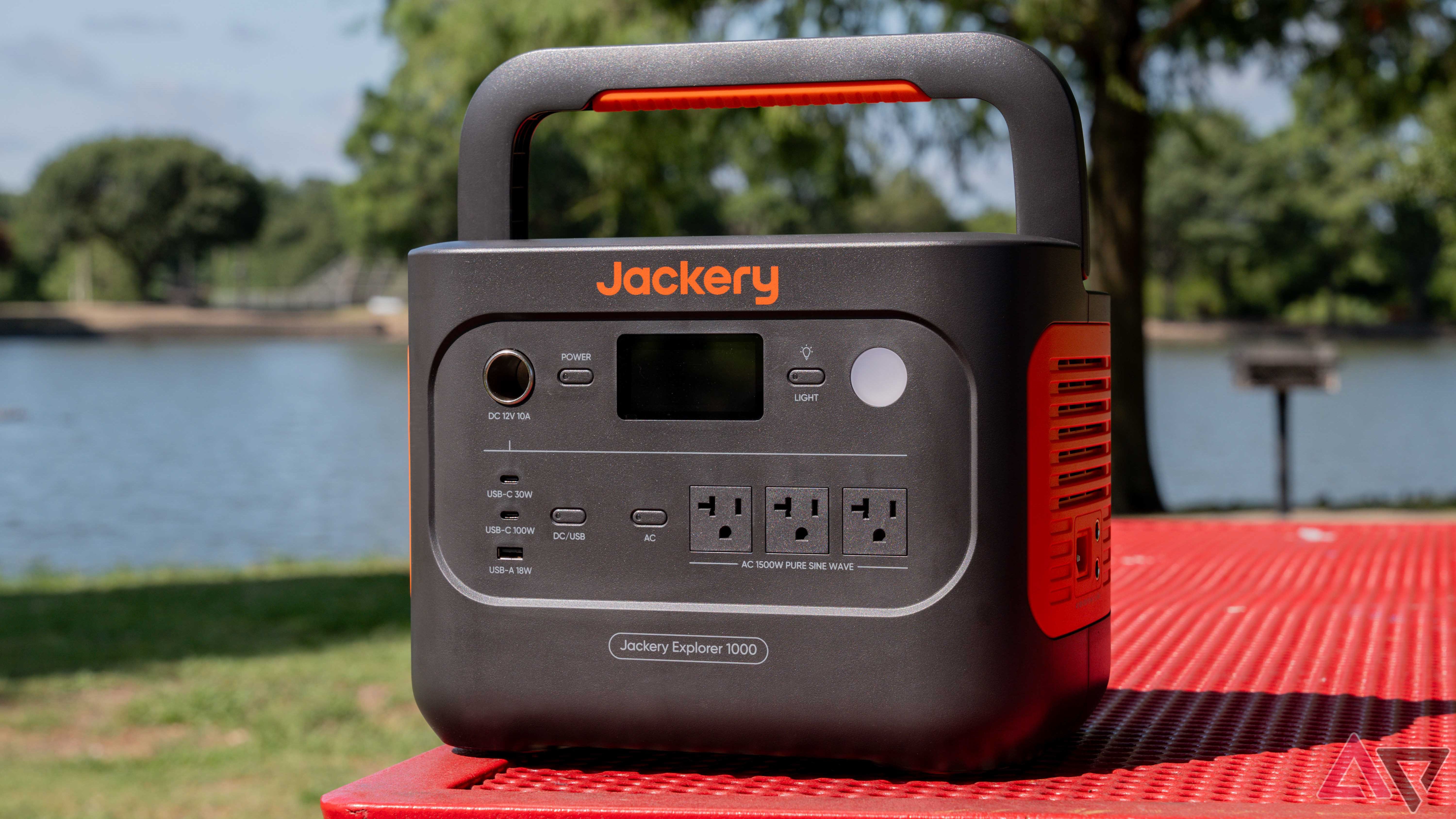 The Jackery Explorer 1000 v2 on a red park bench with a lake in the background