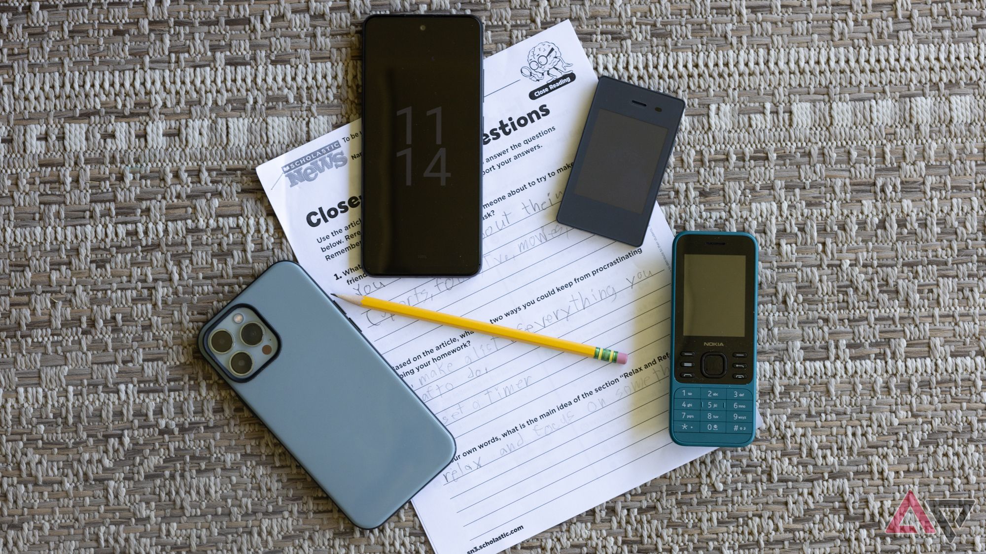 Four phones lying on top of a child's homework