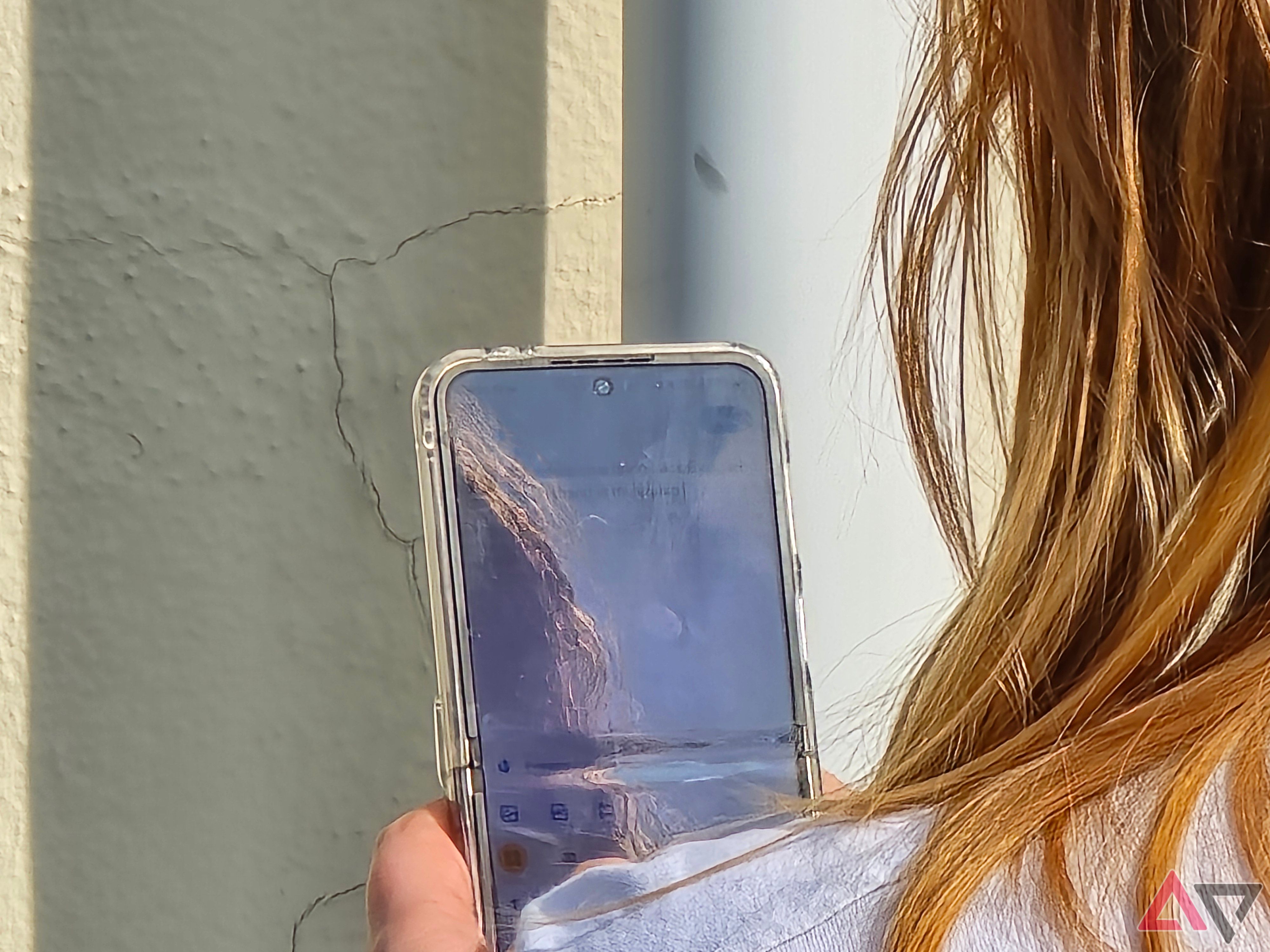 A photo of a woman holding a Galaxy Z Flip 5, the photo is zoomed in and lacks detail