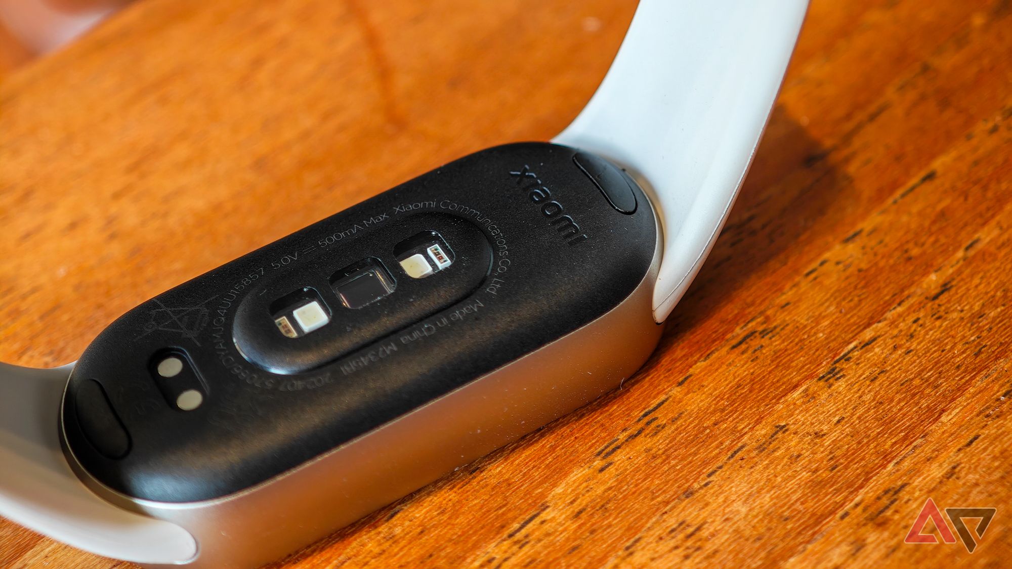 Xiaomi Smart Band 9 lying upside down on a wooden table showing the band attachment points