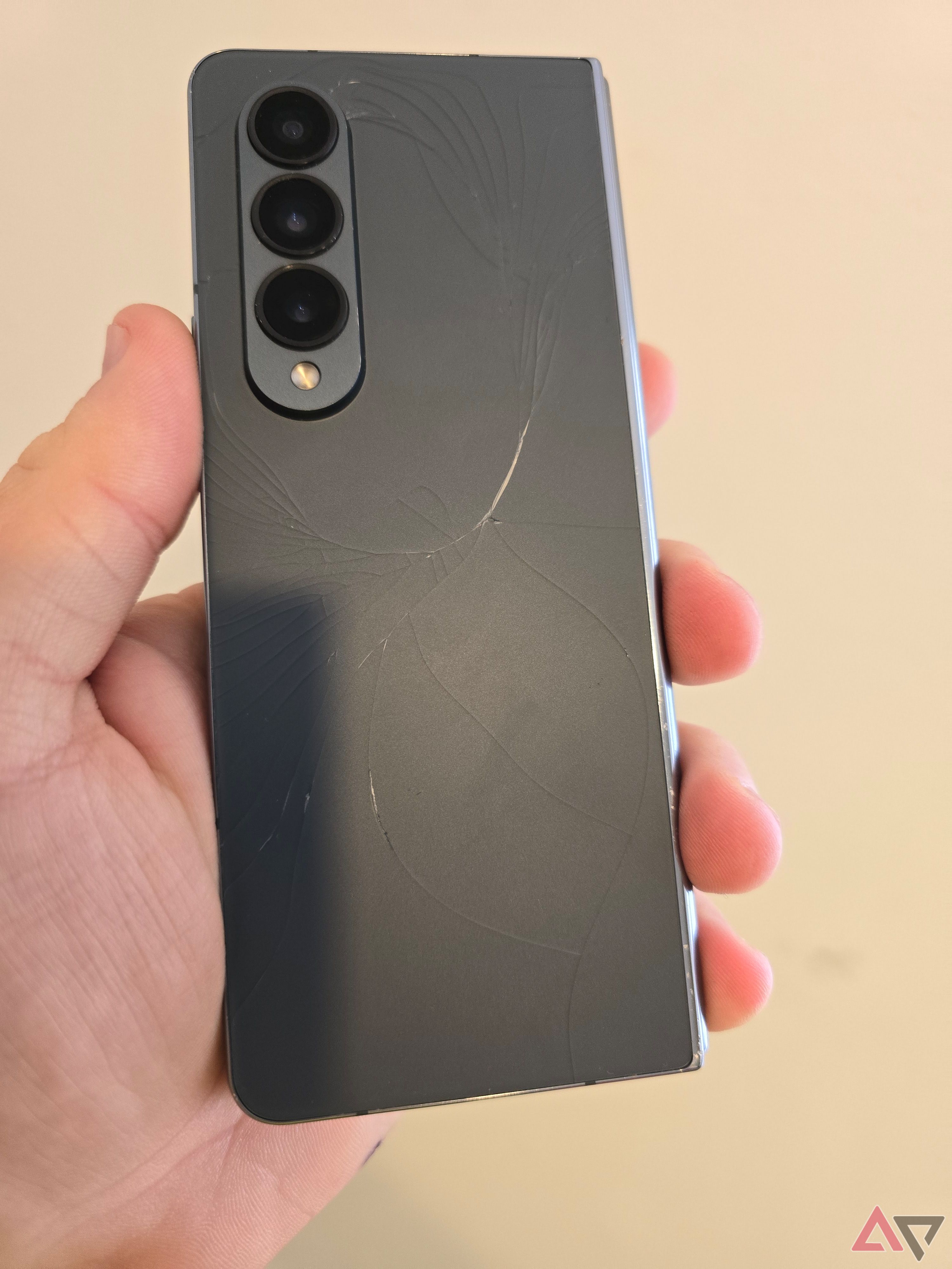 A photo of a green Galaxy Z Fold 4 with a cracked back
