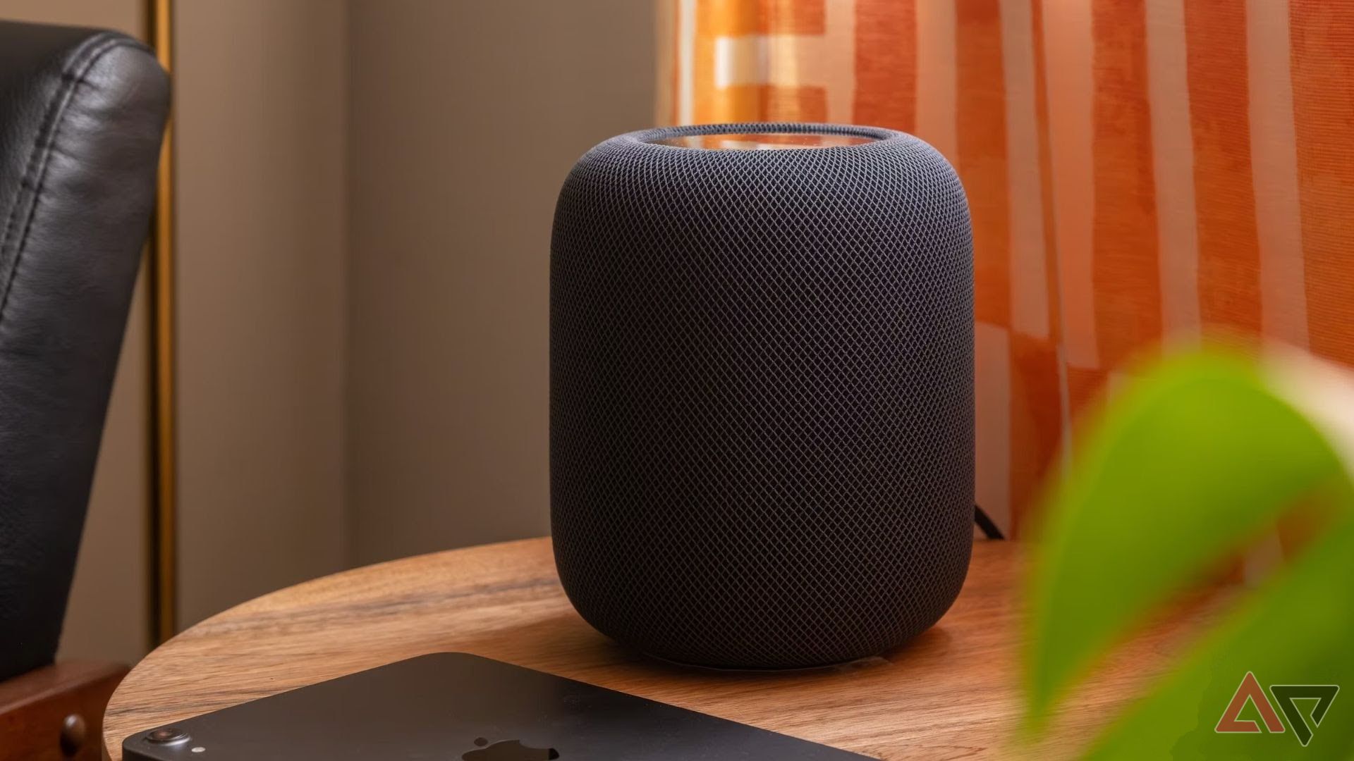 Black Apple smart speaker on a wooden table next to the tablet