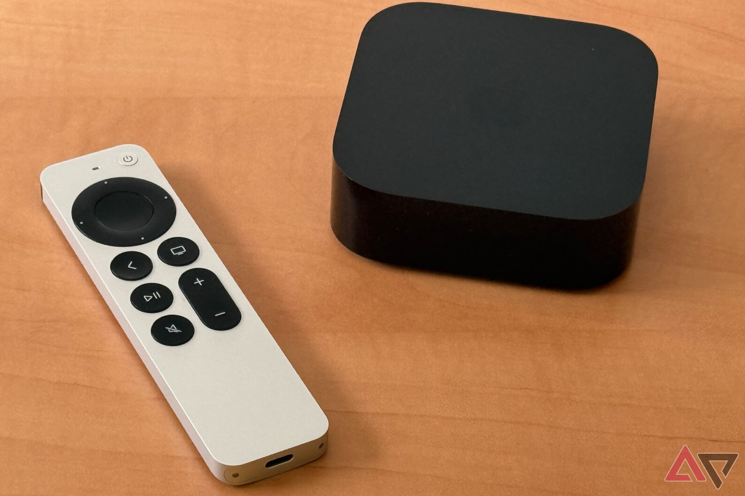 Apple TV 4K and Siri remote on a light brown wooden desk