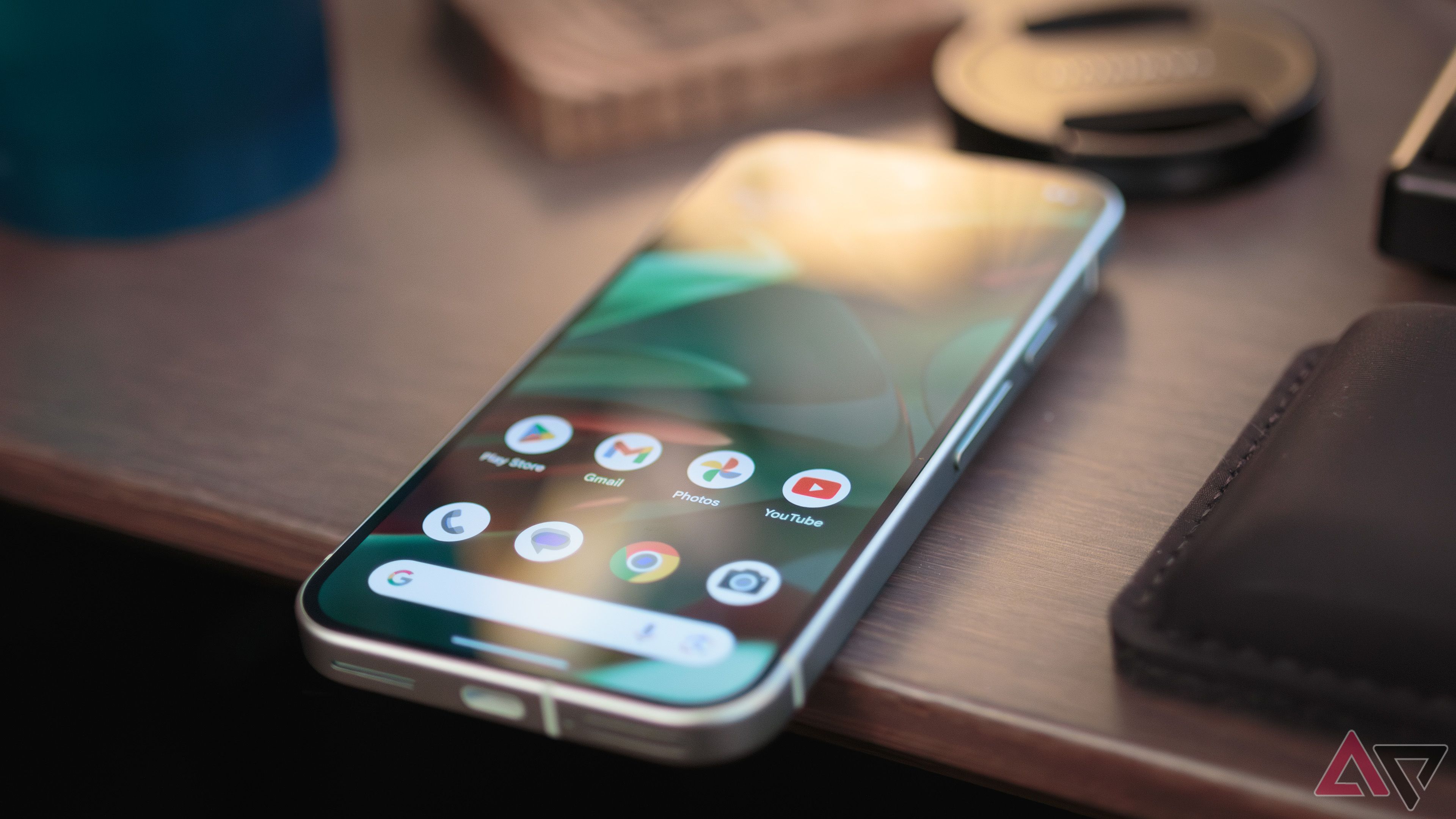 The Google Pixel 9 home screen face up on a wooden desk.