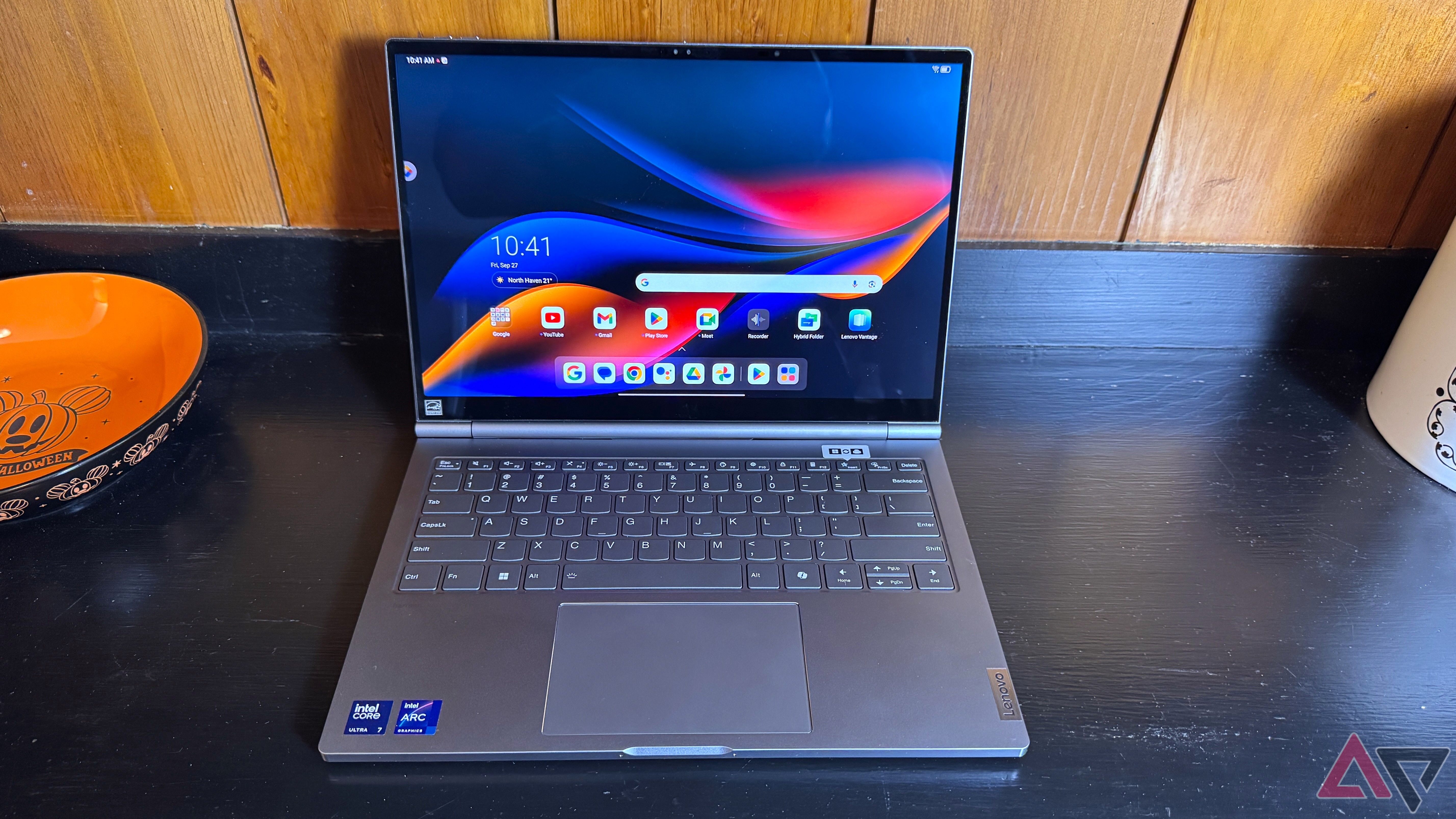 Lenovo ThinkBook Plus Gen 5 Hybrid on a black surface with an orange and black candy bowl to the left.