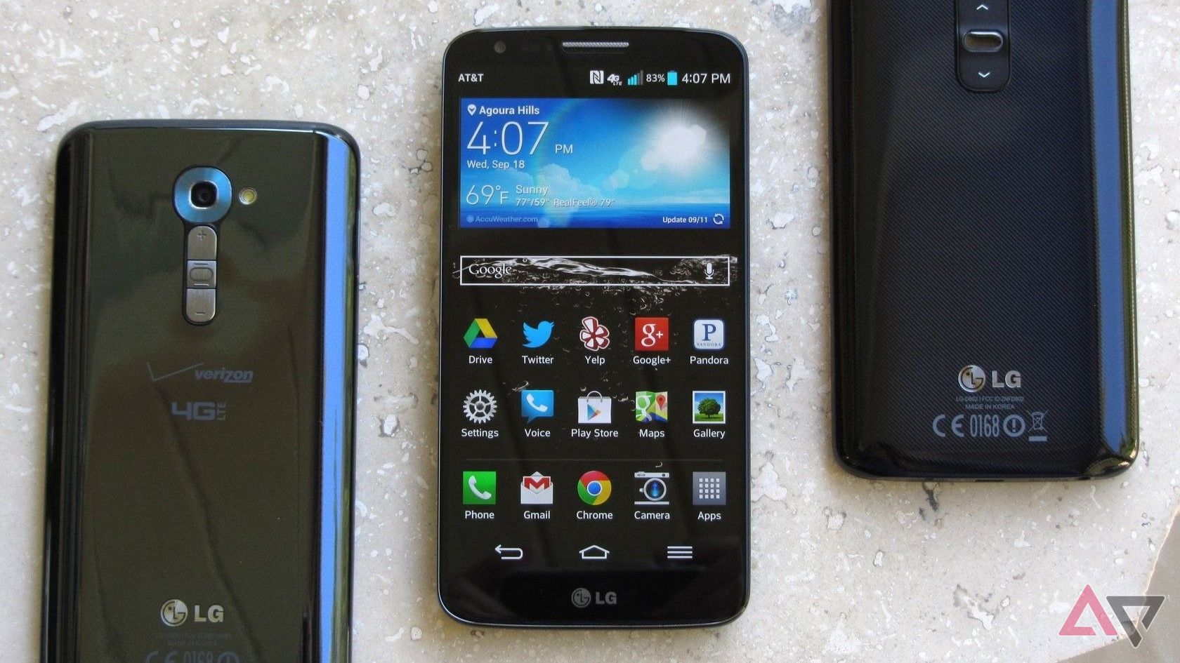 Three LG G2 devices placed on a rock.