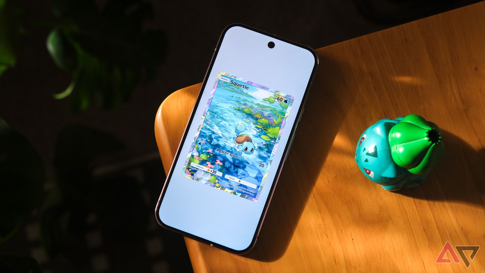 phone showing Pokemon TCG Pocket game resting on wood table