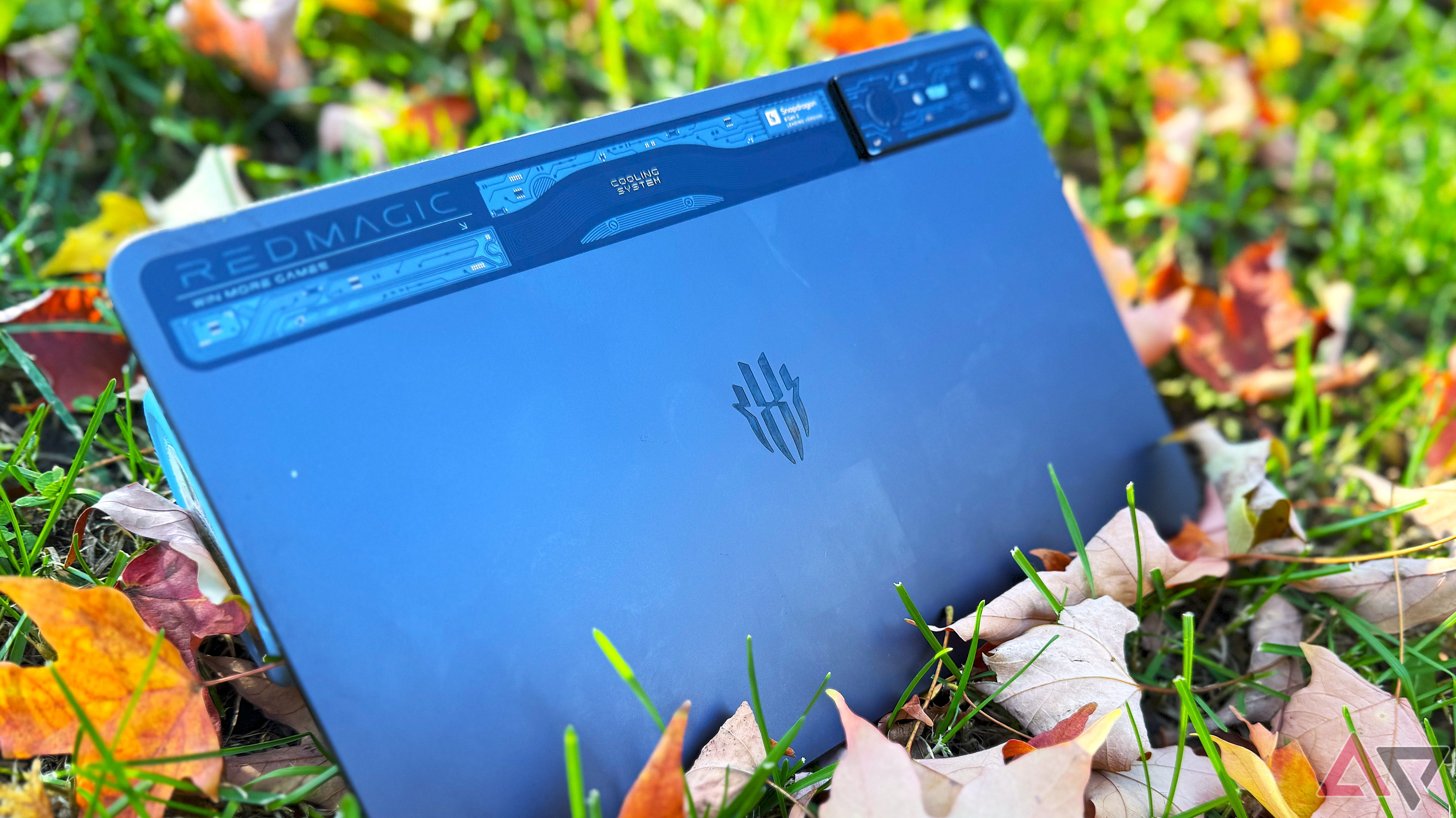 A black Redmagic Nova gaming tablet in some grass surrounded by fall leaves.