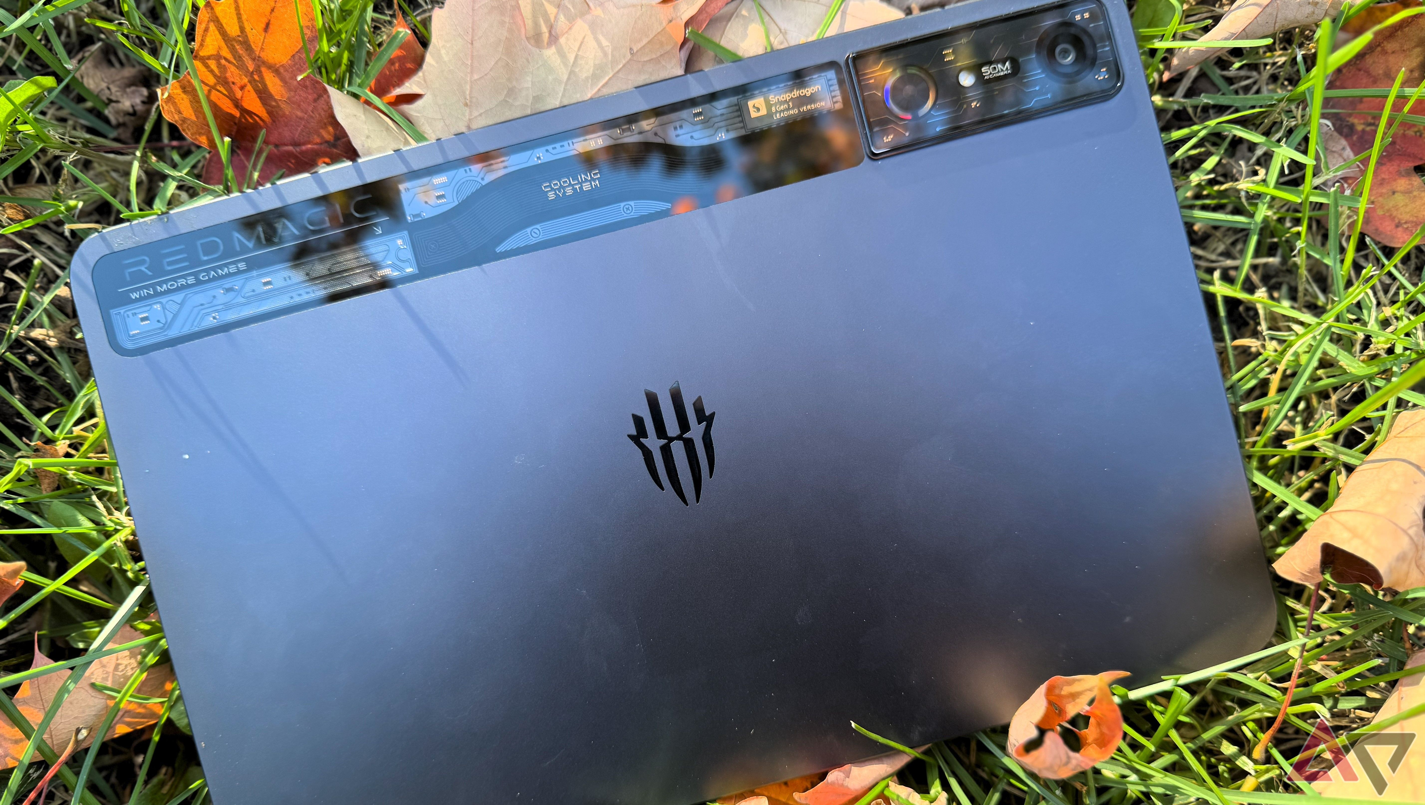 A black Redmagic Nova gaming tablet in grass surrounded by fall leaves.