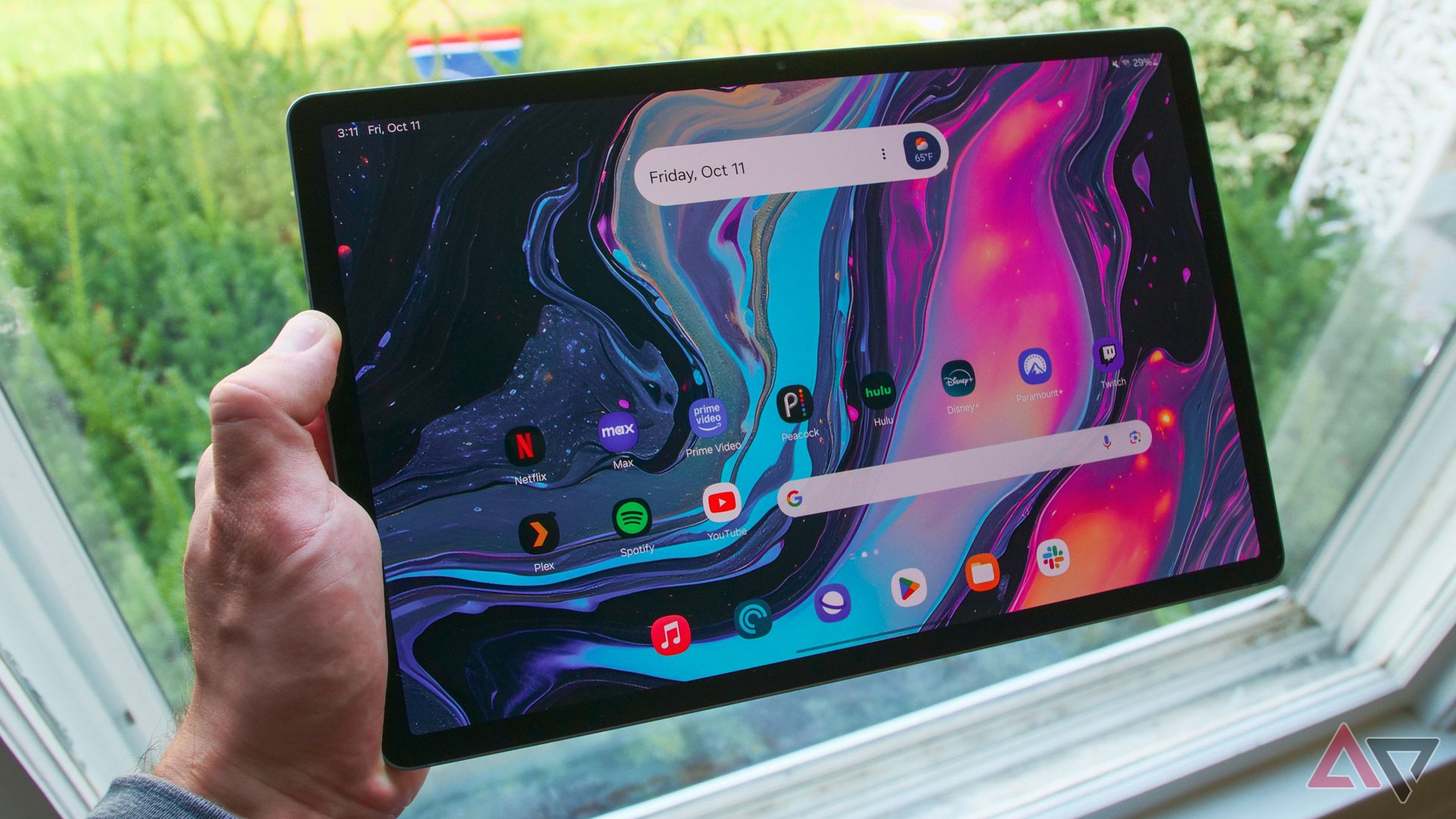 The Galaxy Tab S10+ in a hand held by a window.