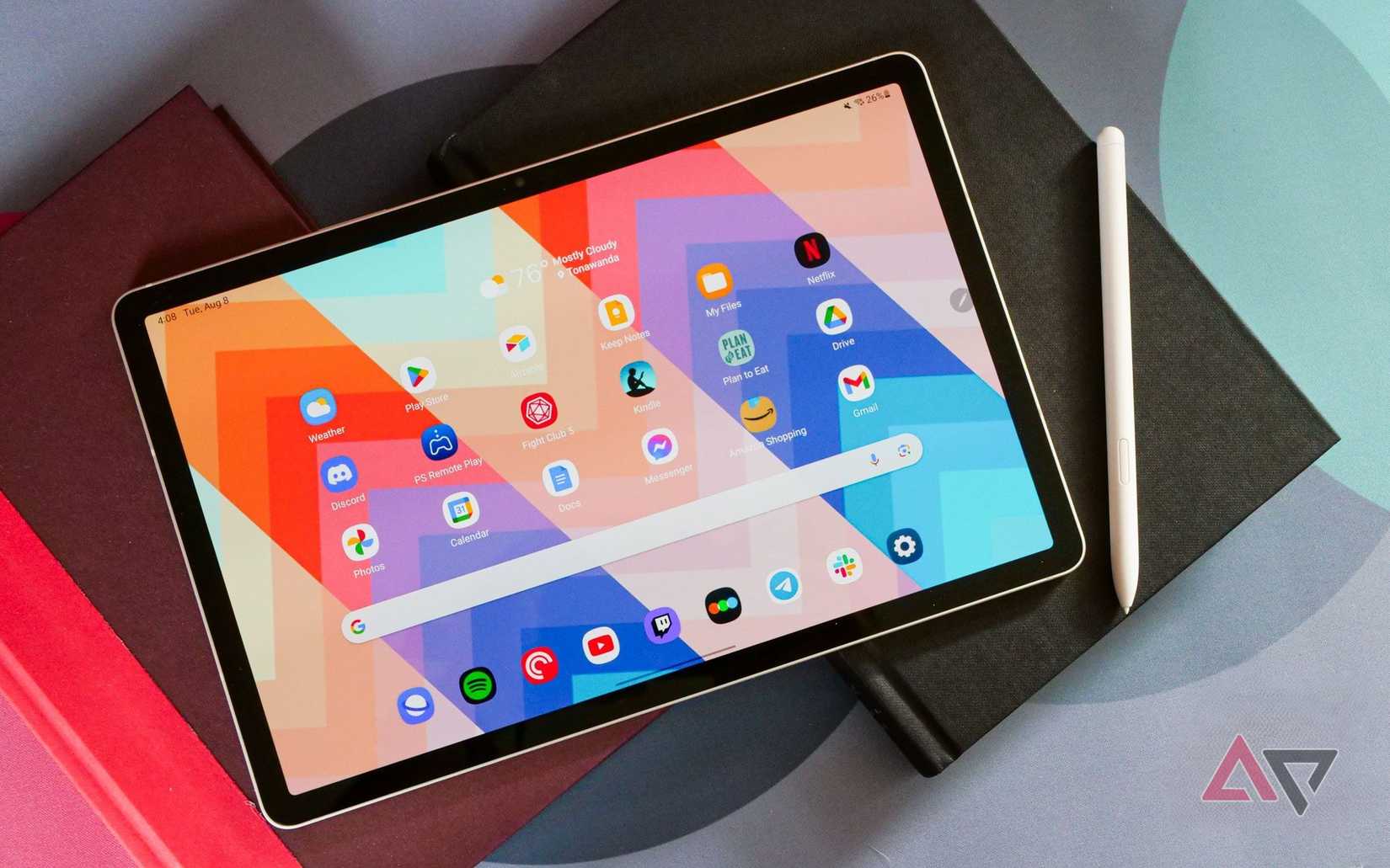 galaxy tab s9 laying on books with colorful background, pen to the side